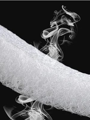 Close-up of a cigarette with smoke rising from it against a black background.