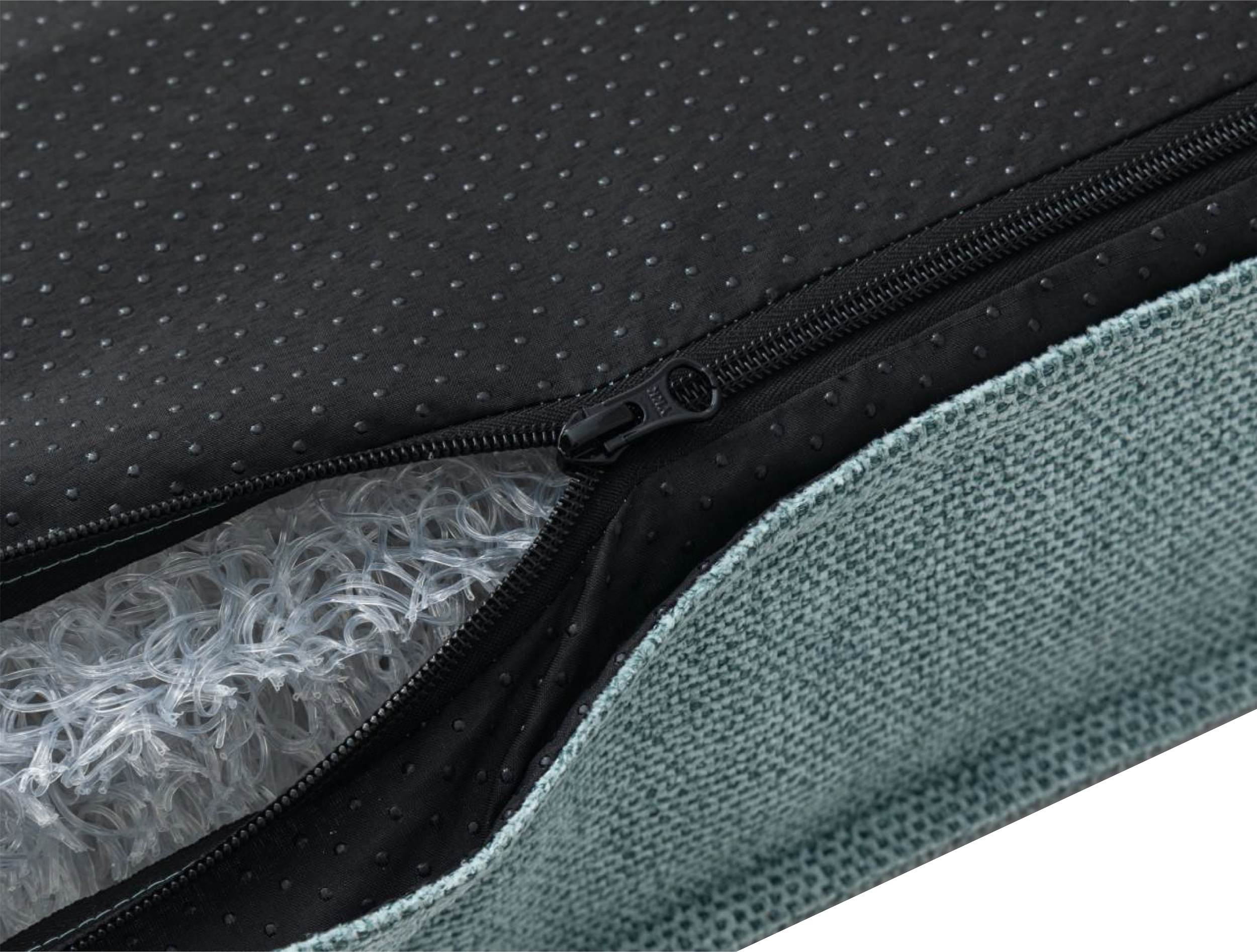 Close-up of a black fabric surface with small raised dots, featuring a black zipper and a textured fabric beneath.