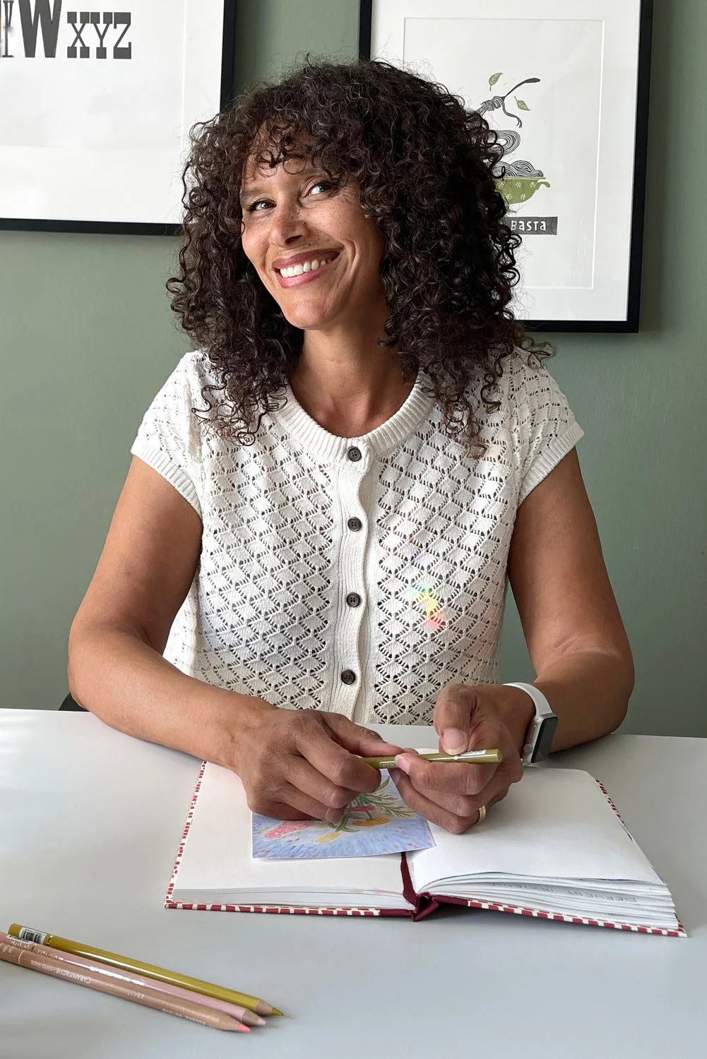 Maruga Koops, illustrator and illustration coach, working at her studio desk in Utrecht with colored pencils and a sketchbook.