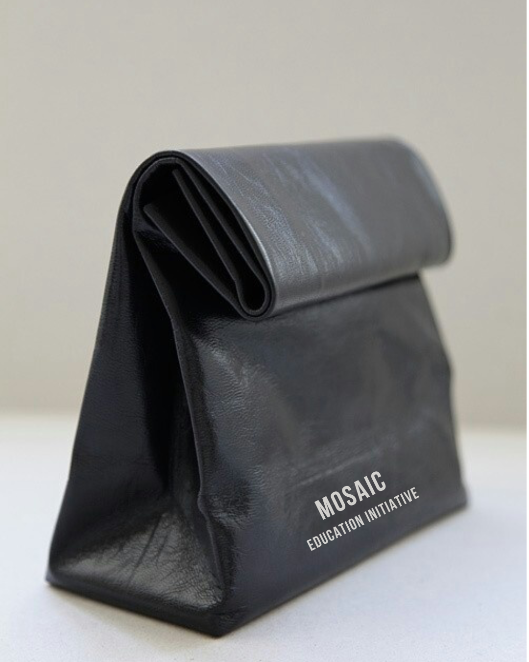 Black bag with a rolled top, labeled 'MOSAIC EDUCATION INITIATIVE' in white text.