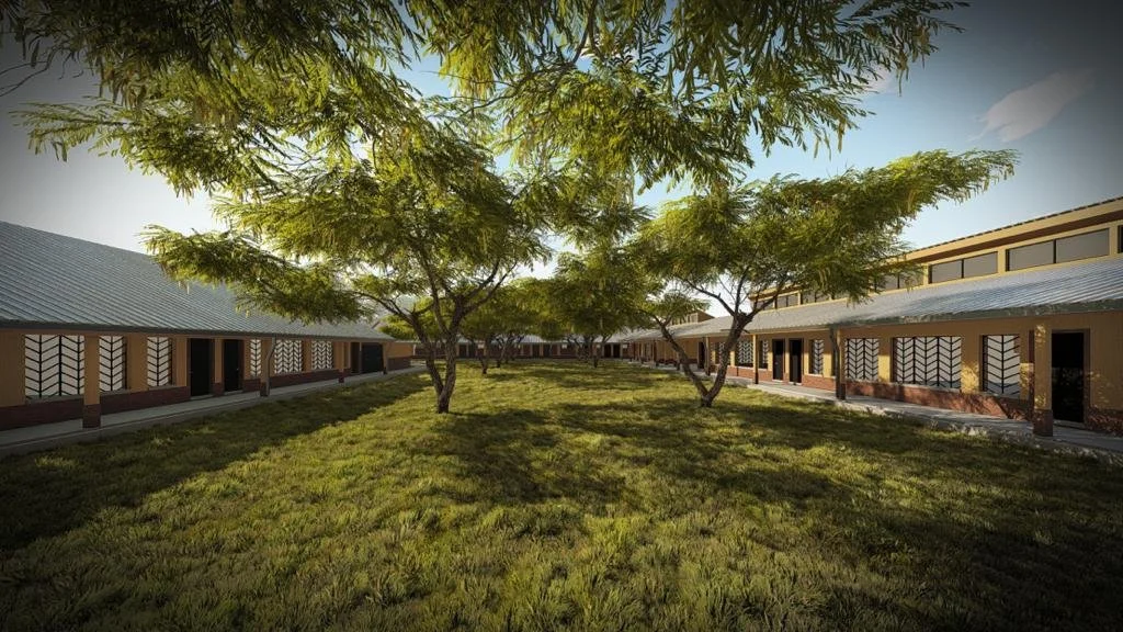 A peaceful courtyard with green grass and trees flanked by single-story buildings with large windows and metal roofs.