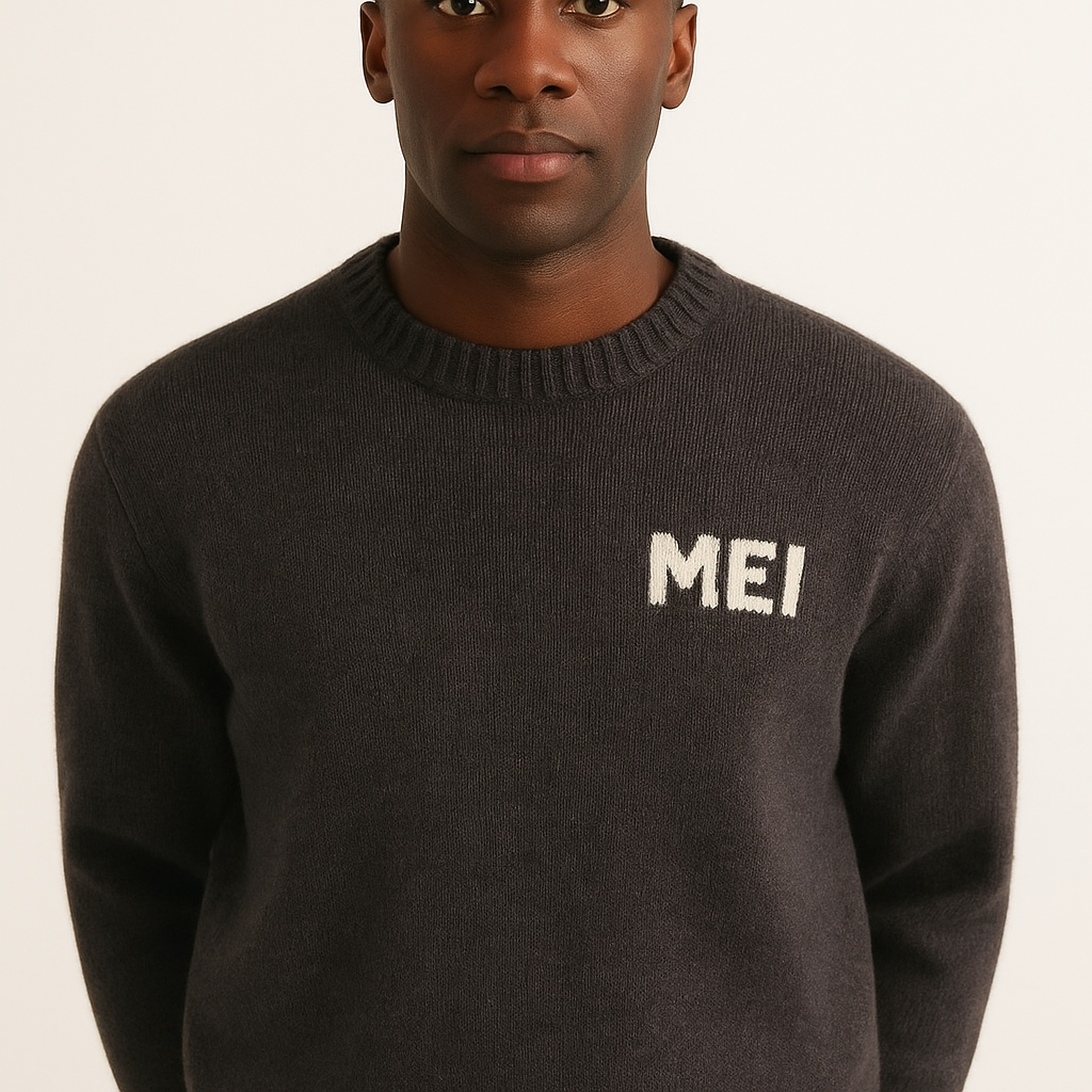 A person wearing a dark sweater with the name 'MEI' embroidered on the upper right side.