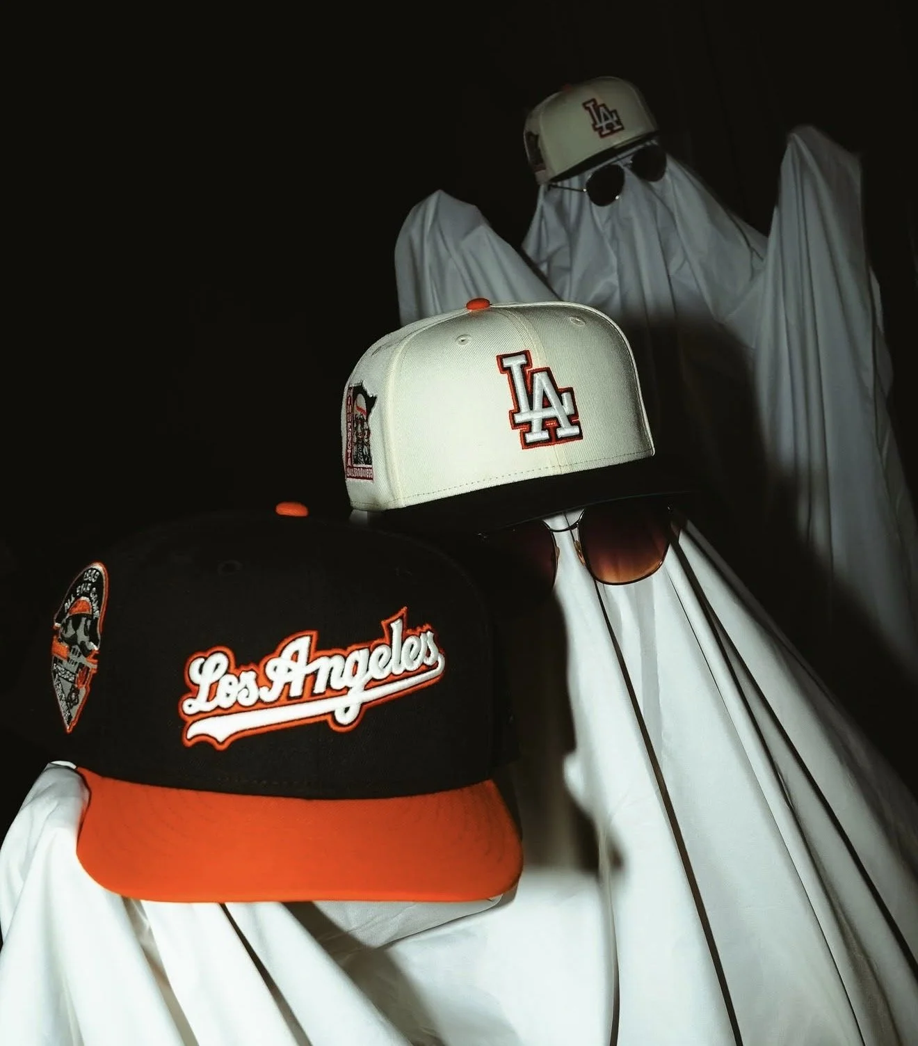 Los Angeles Dodgers baseball caps and sunglasses displayed on white ghost-like figures against a dark background