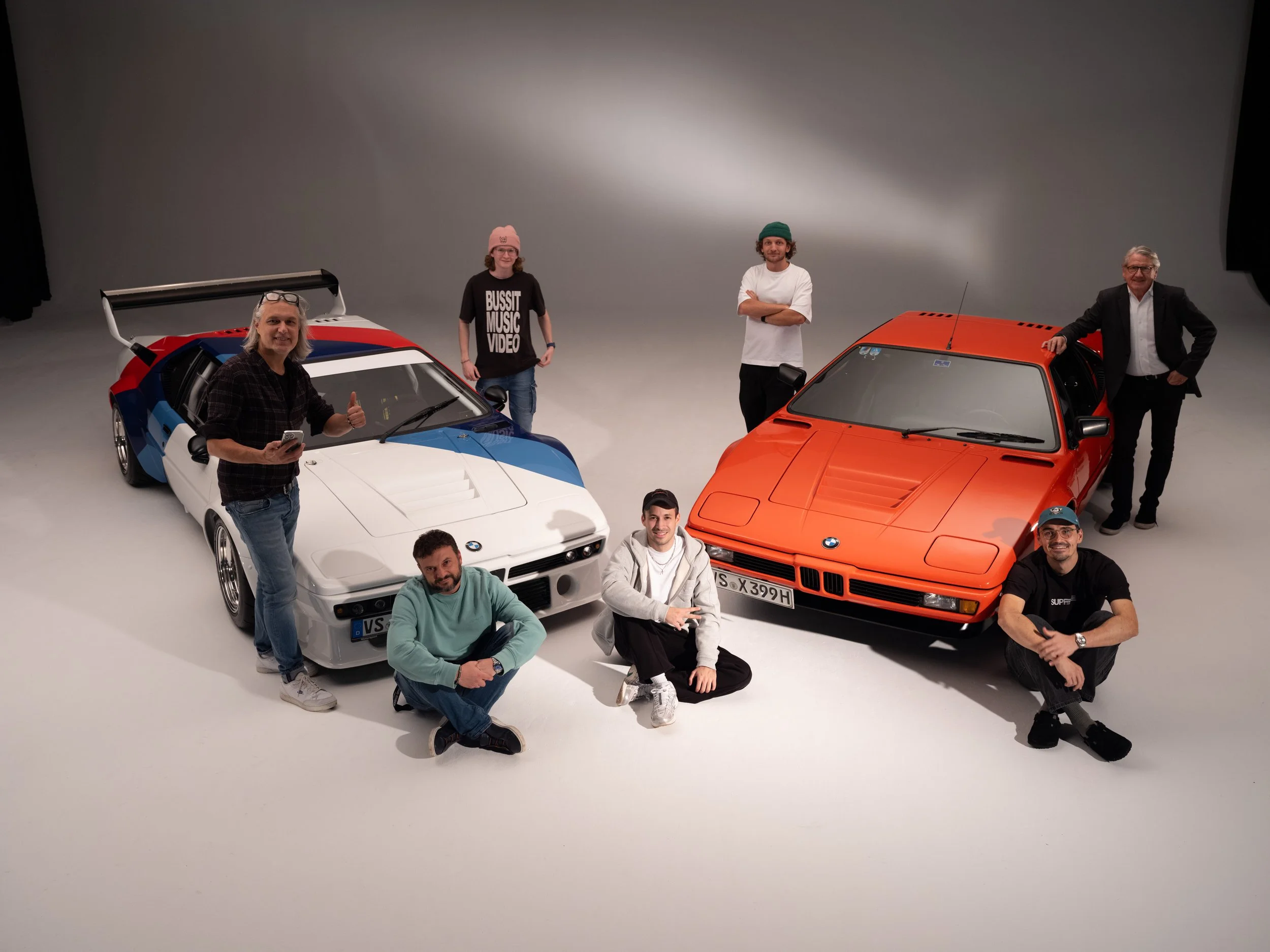 Gruppe von sieben Personen neben zwei restaurierten M1 BMW-Autos in einem Fotostudio von René Staud