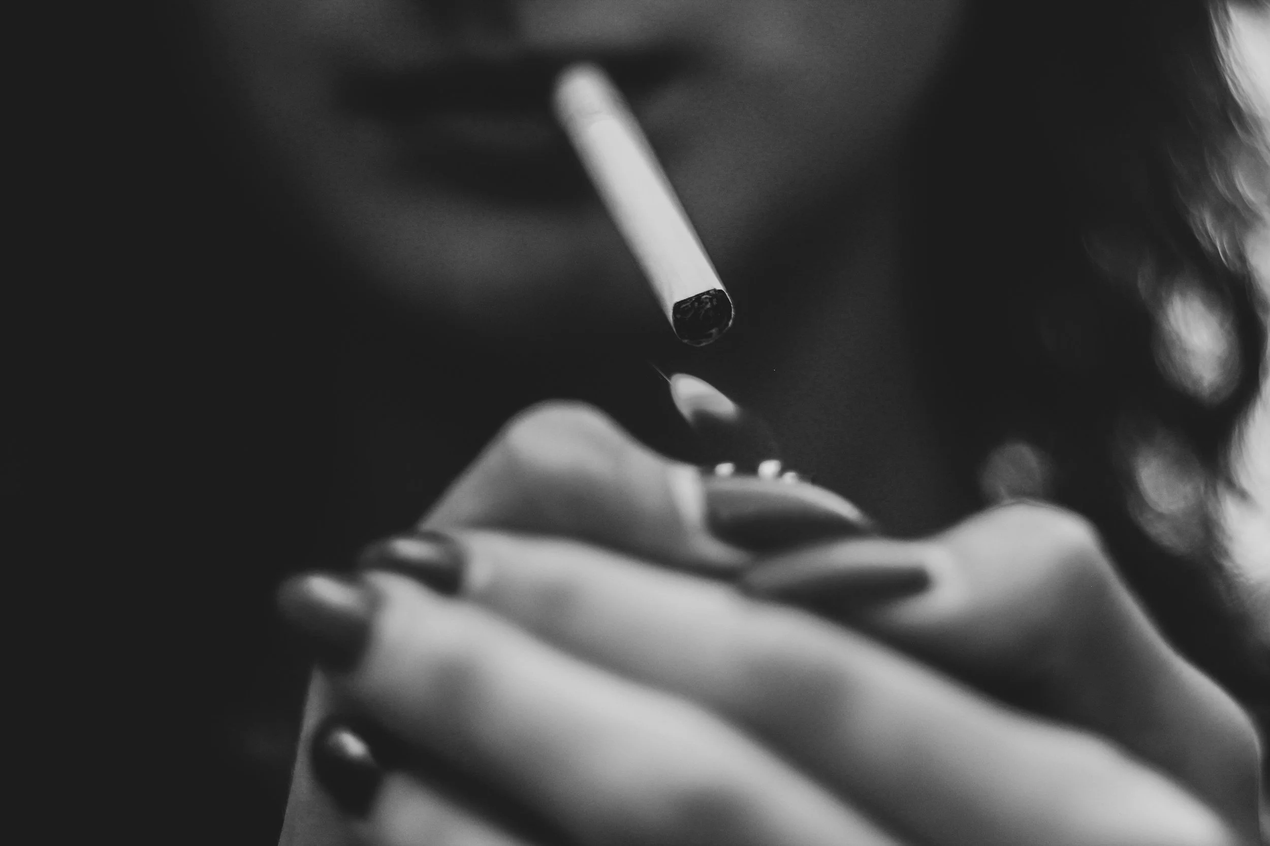 Close-up of a person smoking a cigarette in black and white.