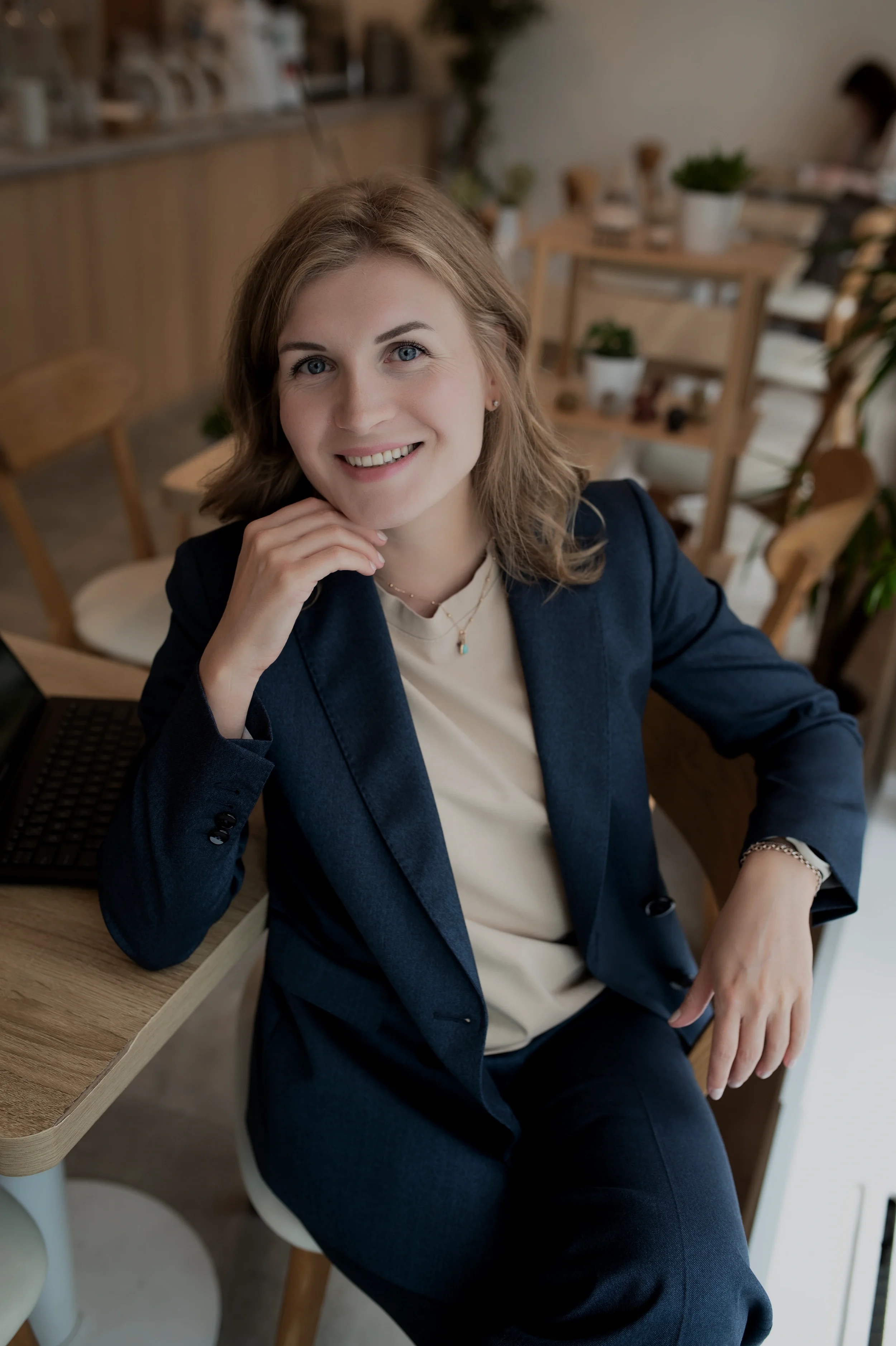 VIMA Digitalin yrittäjä hymyilee istuessaan kahvilaympäristössä läppärin äärellä. Ammattimainen digimarkkinoinnin asiantuntija palveluksessasi.