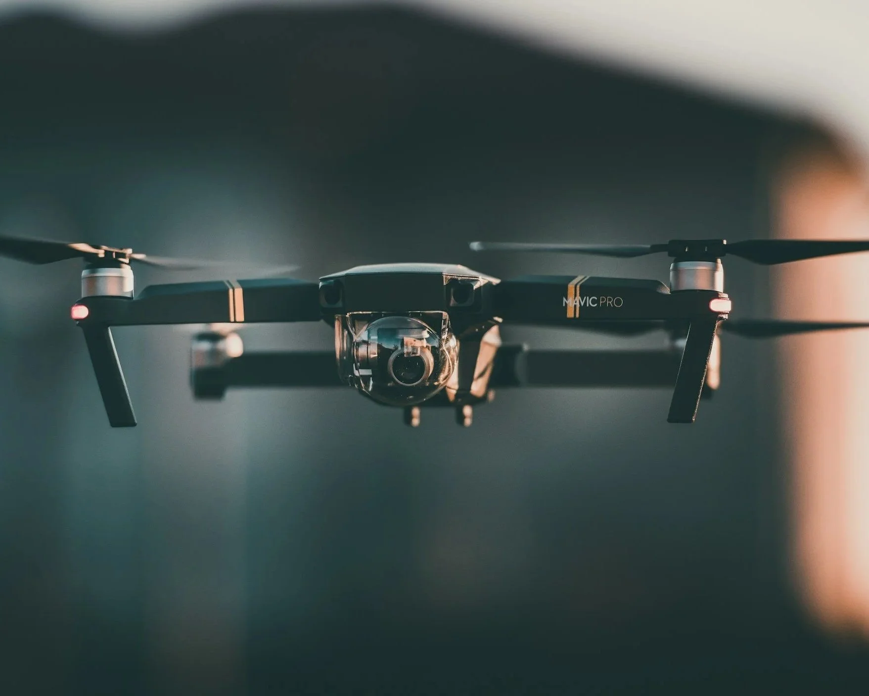 Close-up of a DJI Mavic Pro drone flying indoors, with a blurred background and soft lighting.