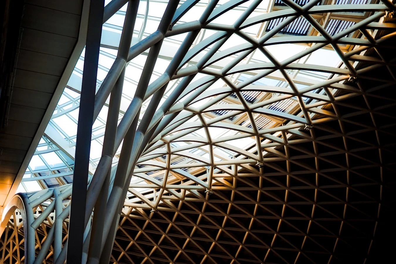 Interior view of a modern architectural building with a curved steel framework and large glass windows allowing natural light.