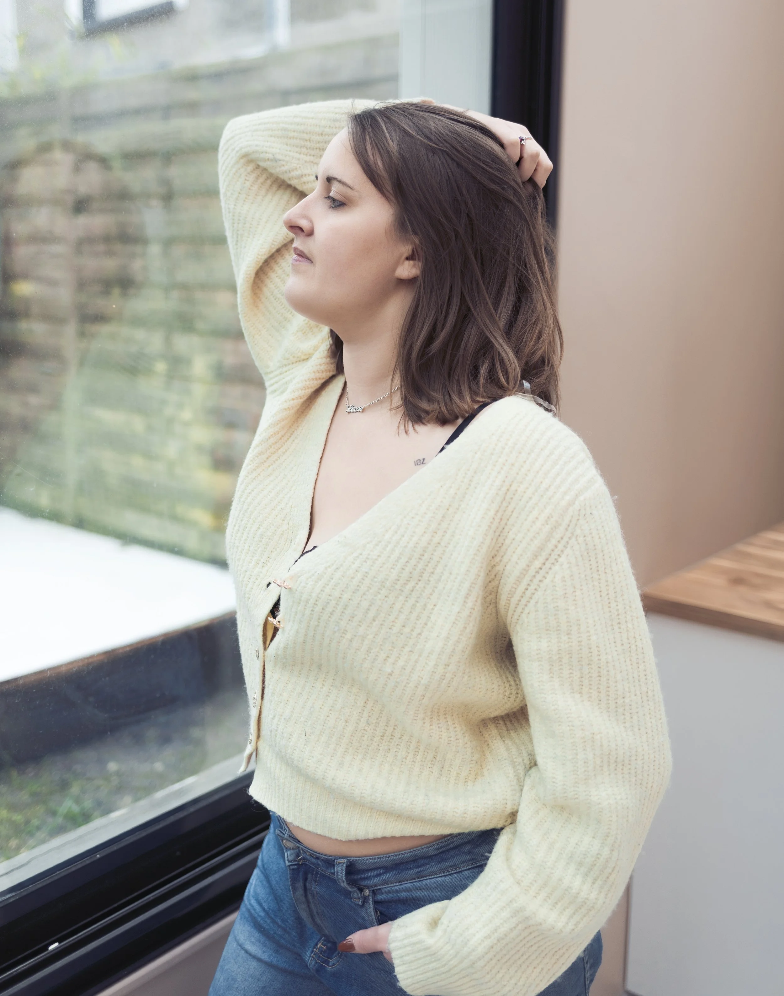 personne posant avec un gilet jaune et un jean devant sa fenêtre pour une séance boudoir à Saint-Martin Boulogne