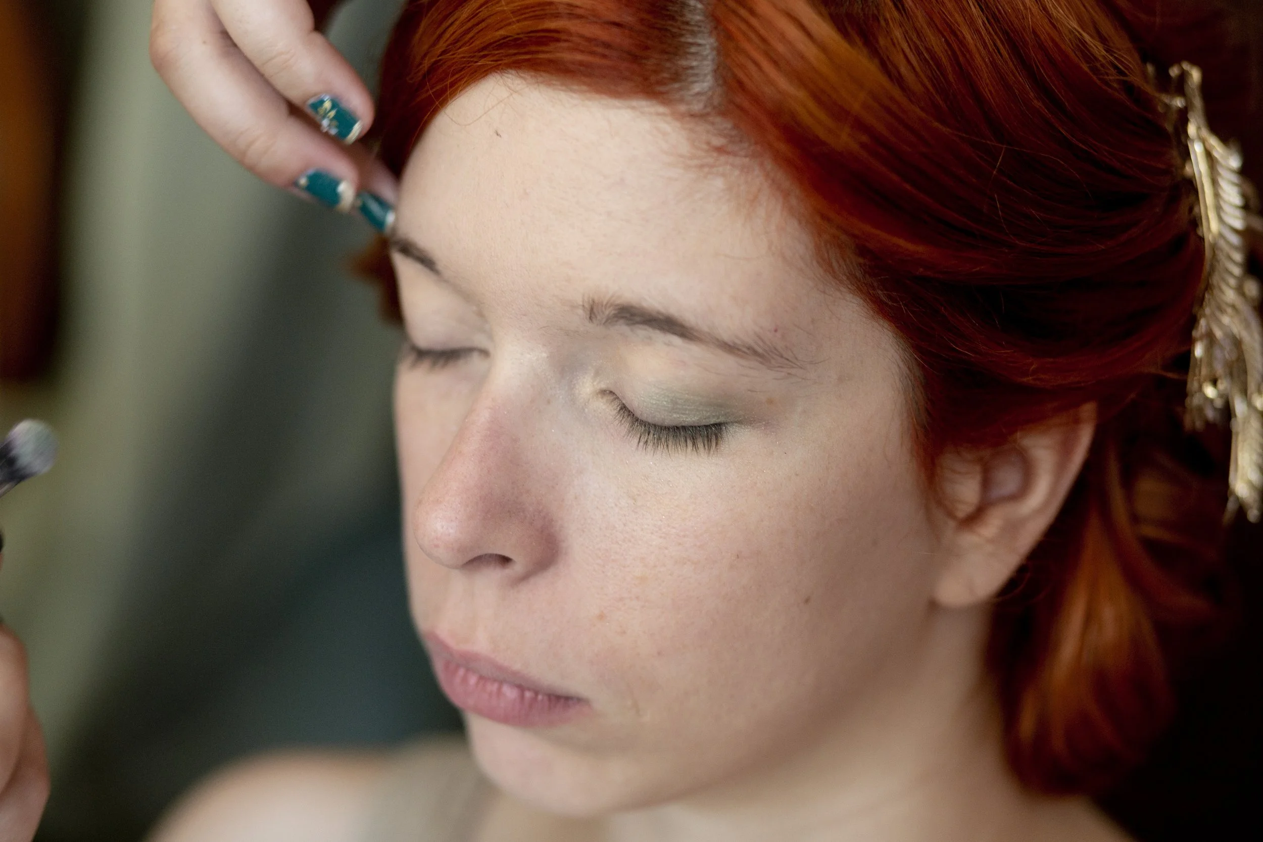 Femme aux cheveux roux se faisant maquiller les yeux avec un maquillage naturel.