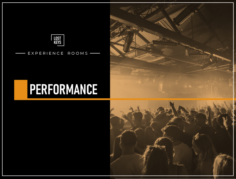 Crowd of people at a concert or performance, with some raising their hands, indoor venue with stage lighting and industrial ceiling.