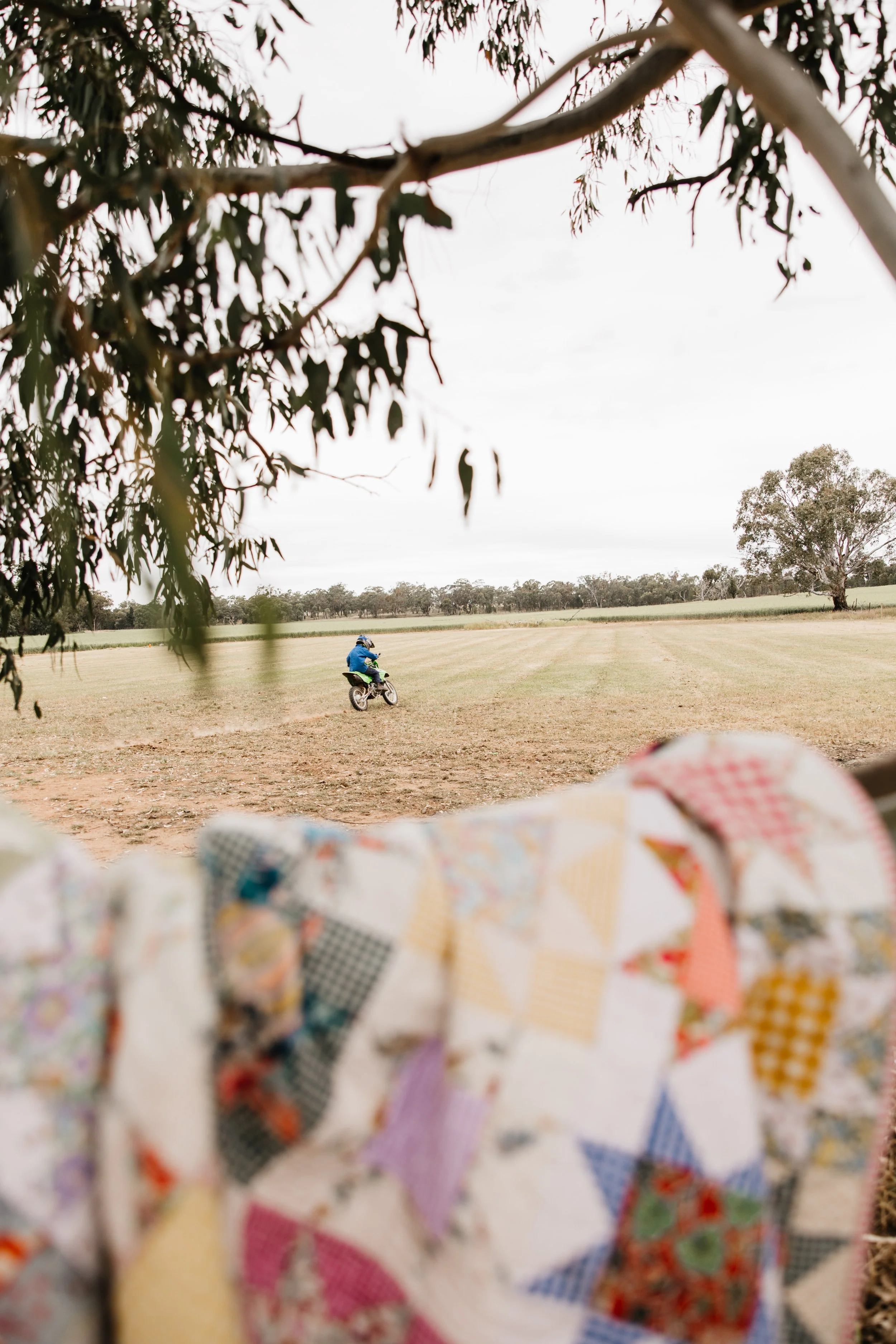 Scenic landscape with a turquoise lake, green rolling hills, and rugged mountains under a cloudy sky.