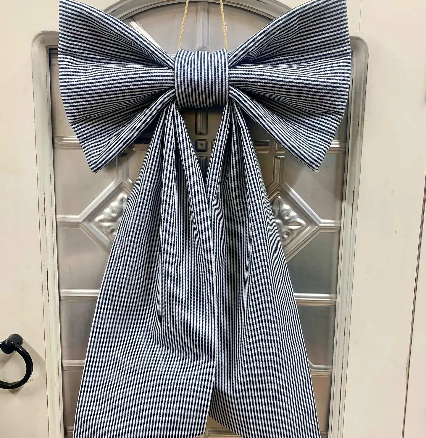 A large navy and white striped bow tie hanging on a door.