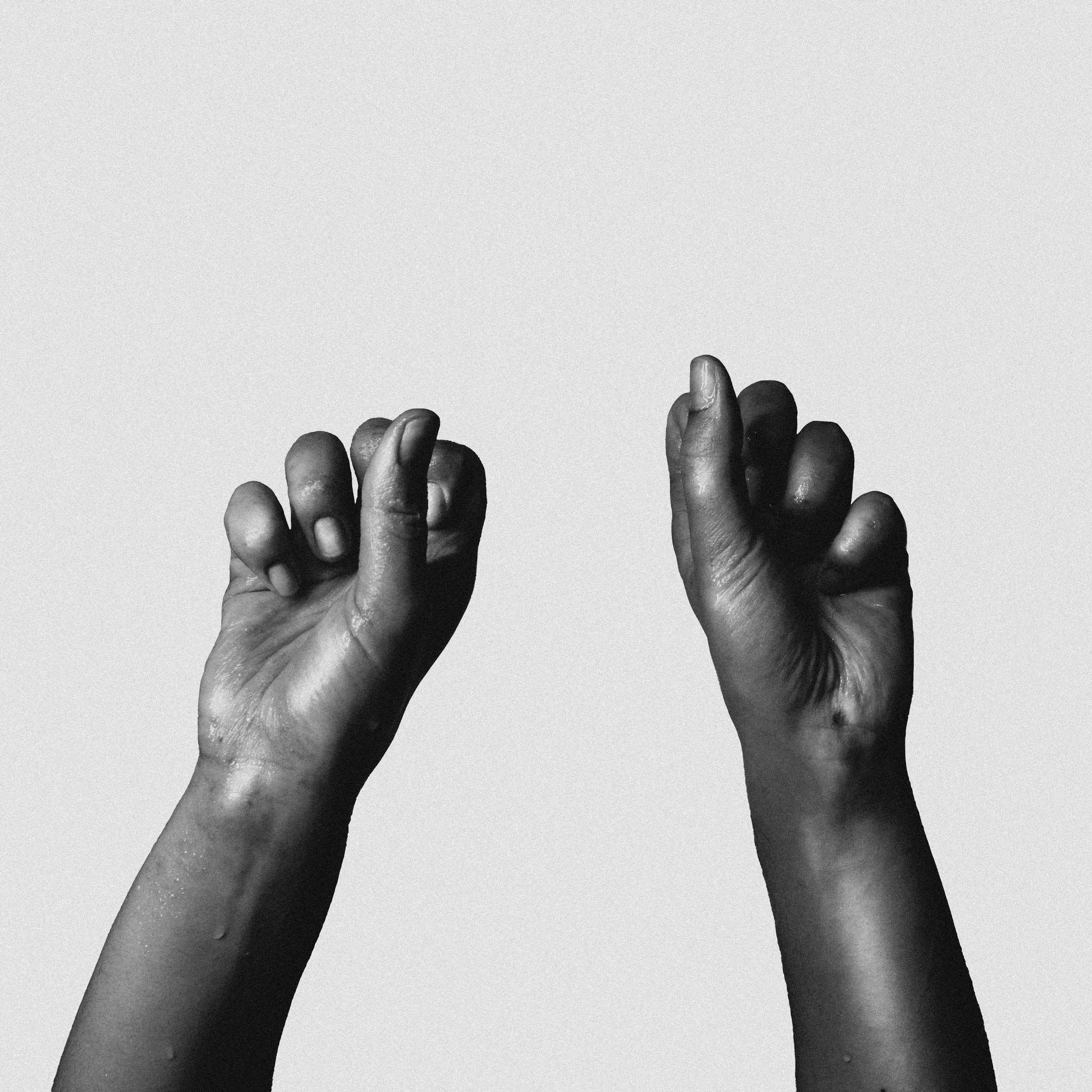 Deux mains noires levées, faisant un geste de poing ou de flexion, avec un fond blanc.