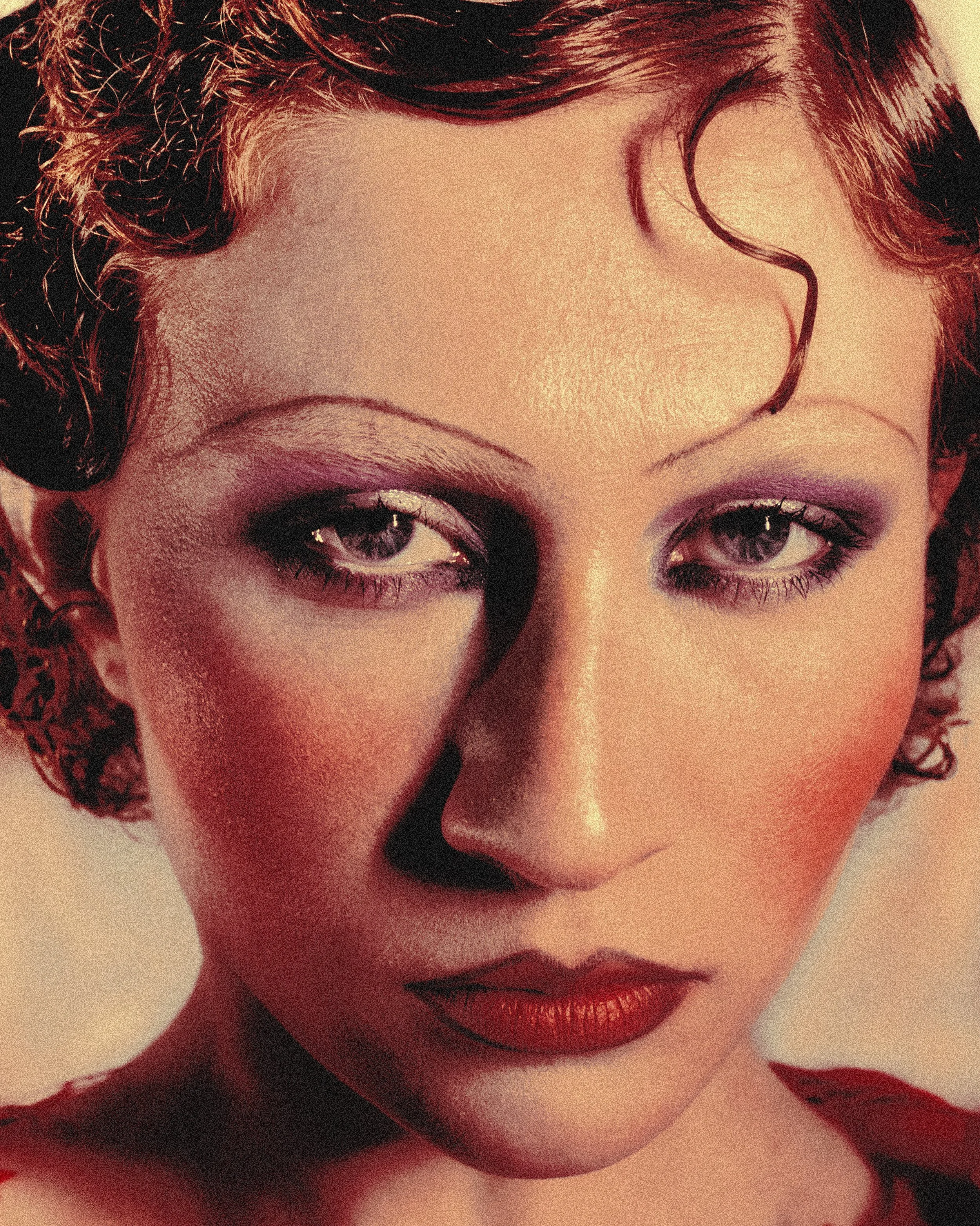 Portrait d'une femme avec maquillage élaboré, cheveux bouclés courts, portant une robe rouge.