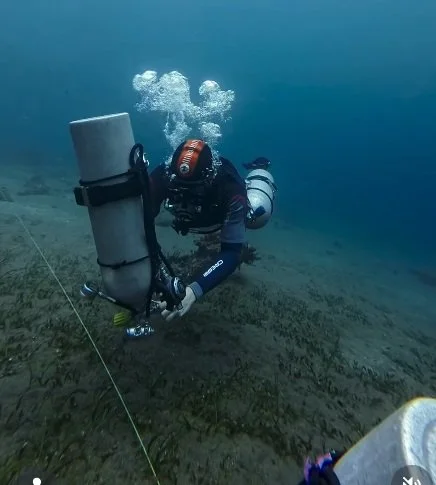 A sidemount diver removing one tank and attaching it to a control line underwater
