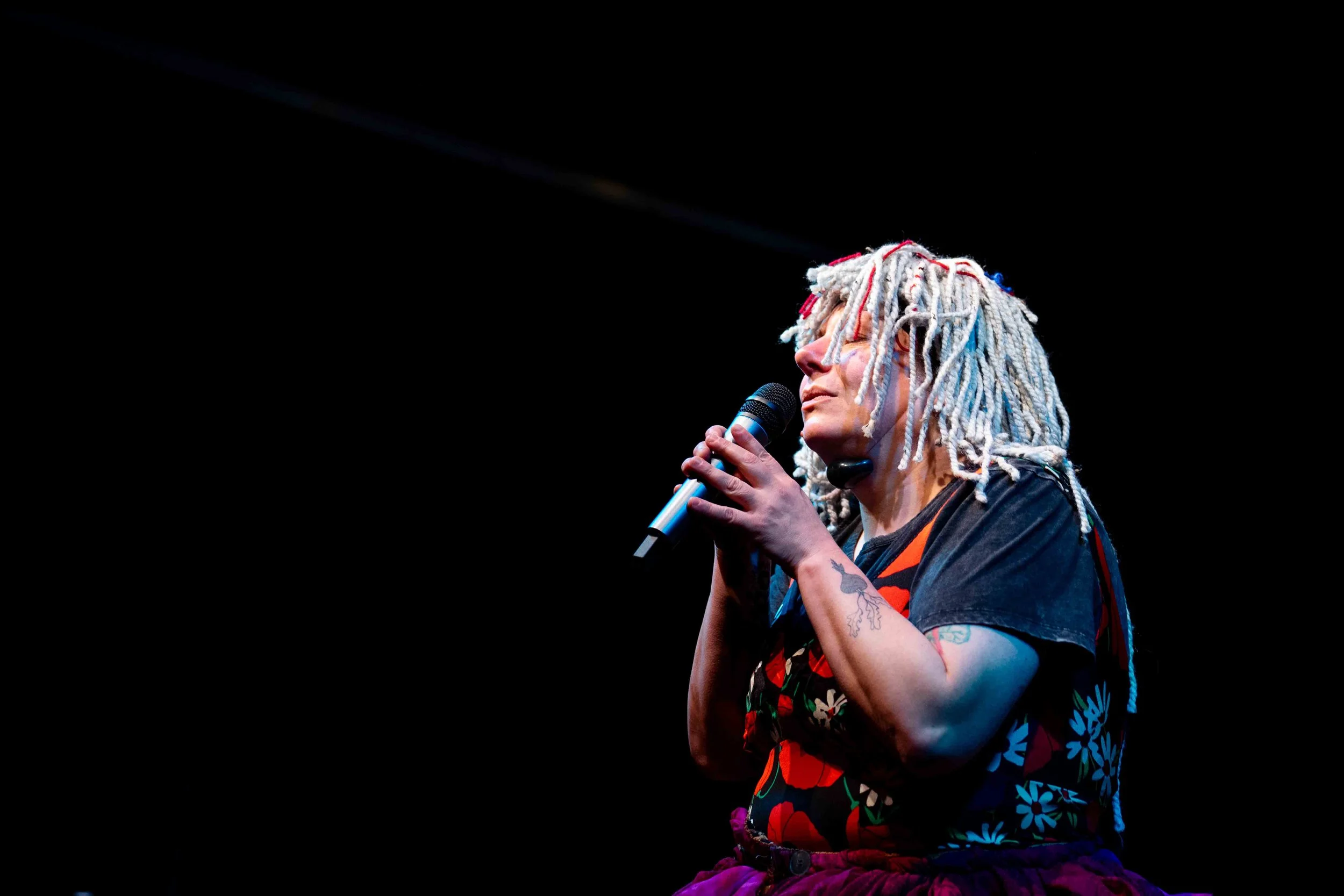 Picture of performer Kathleen Greenfield wearing a clown costume and singing into a microphone