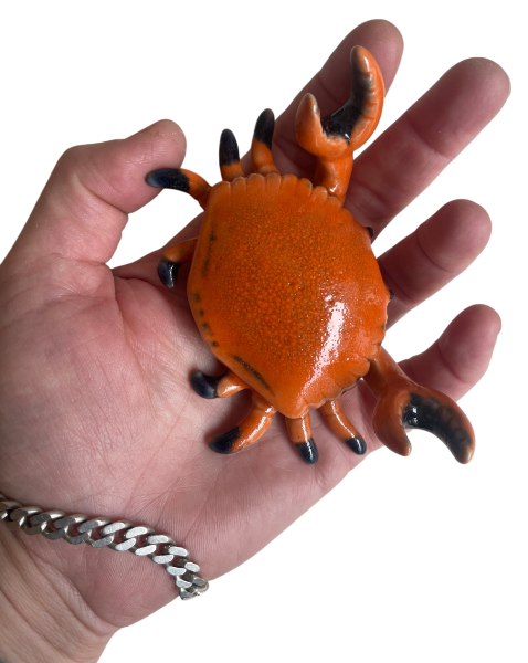 Hand holding a cute ceramic crab in orange