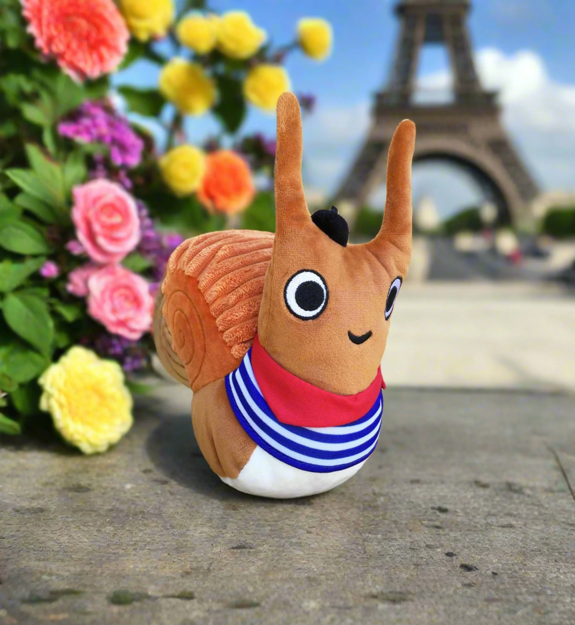 Escargot plush toy inspired by Dashka Slater’s picture book series, shown in front of the Eiffel Tower.