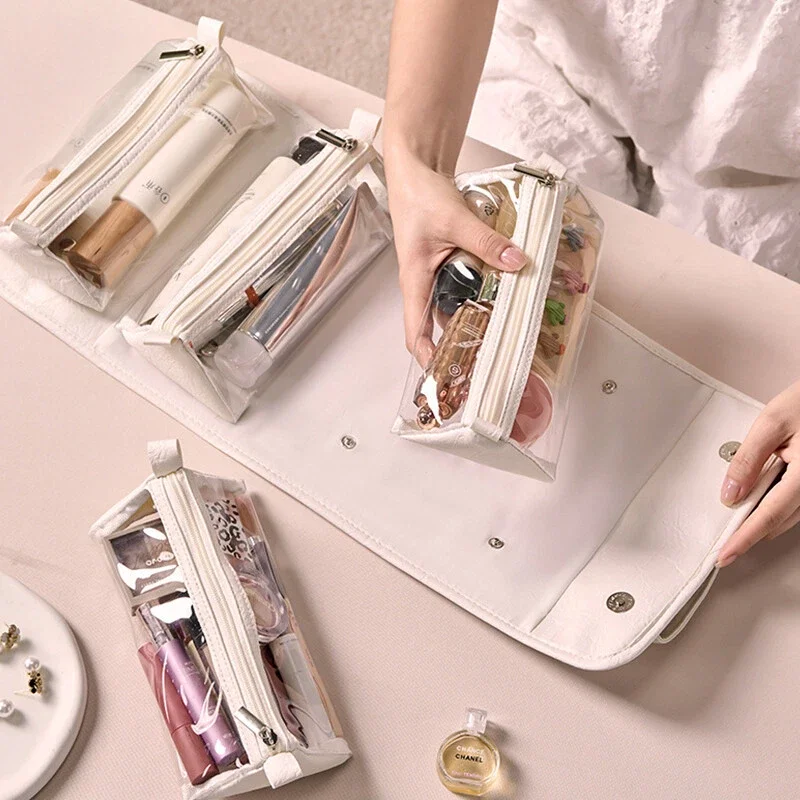 Person organizing transparent zippered pouches with cosmetics and personal care items inside, on a light-colored table.
