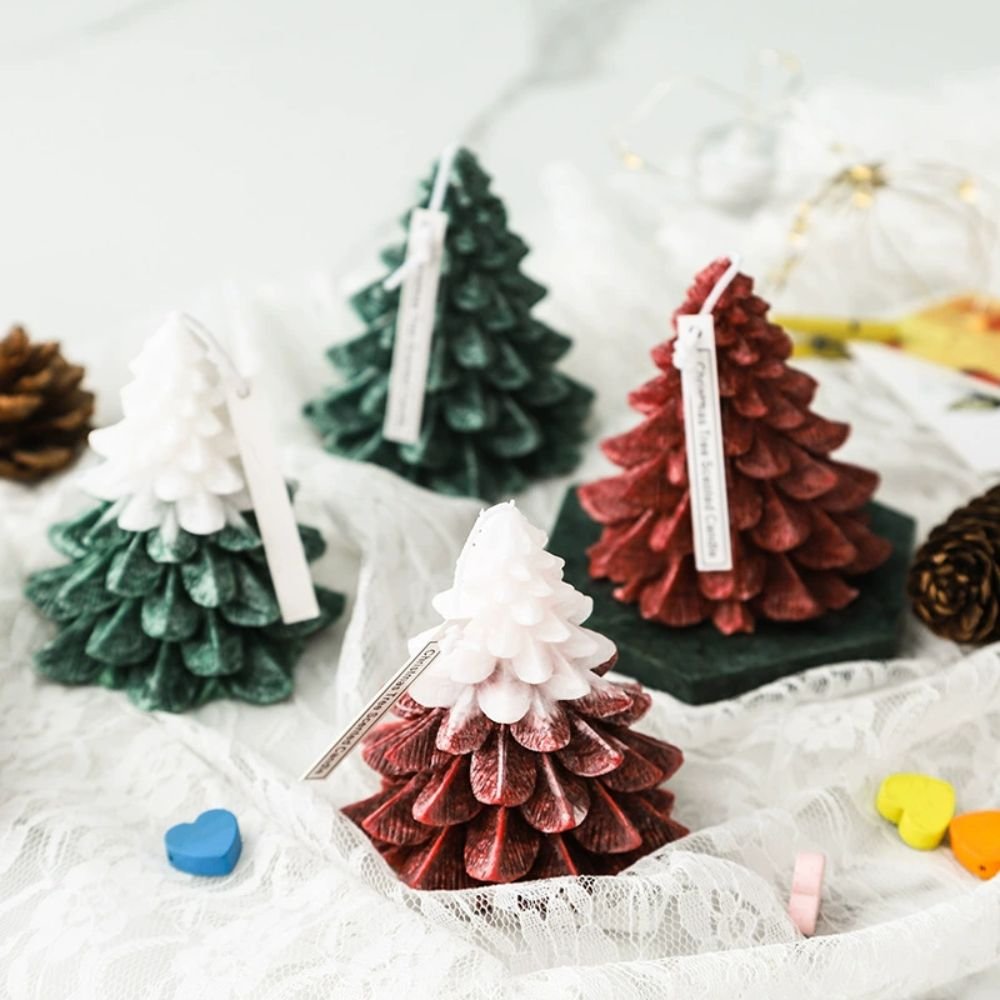 Decorative mini pine tree ornaments in green, white, and red colors displayed on lace fabric with pine cones and colorful heart-shaped objects around.