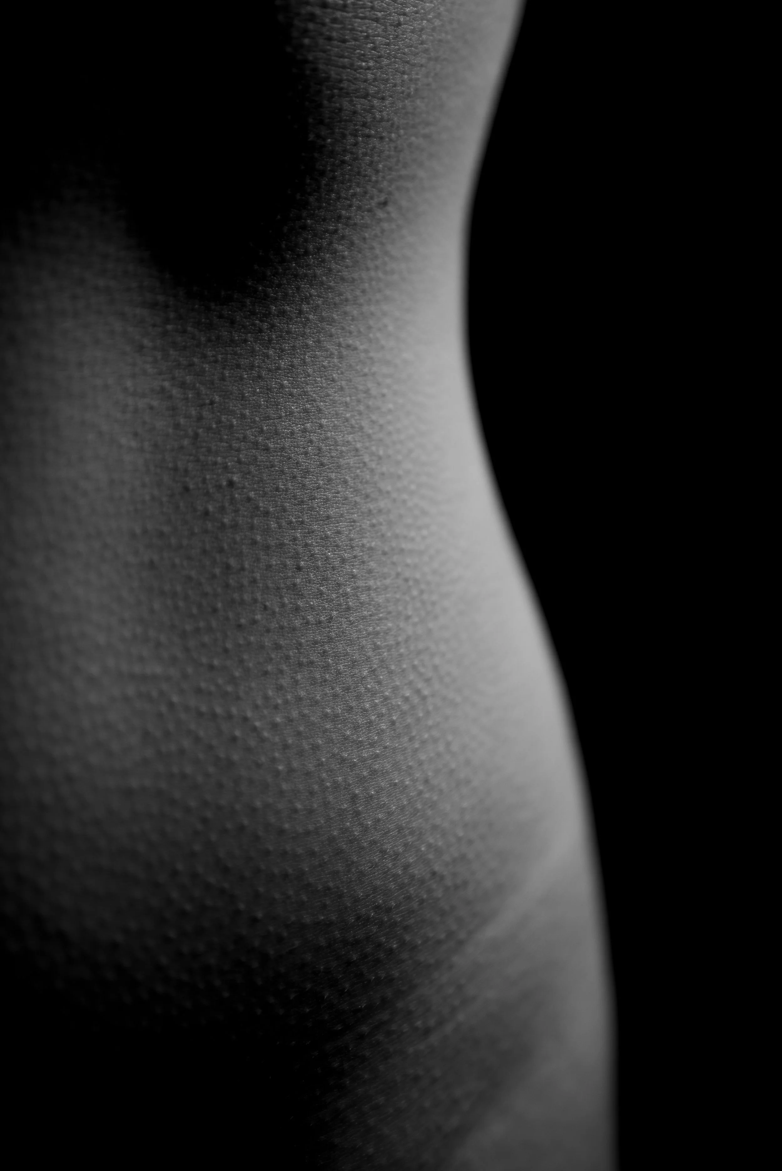 Nahaufnahme eines menschlichen Oberkörpers mit Fokus auf die Hautstruktur, im Schwarz-Weiß-Stil