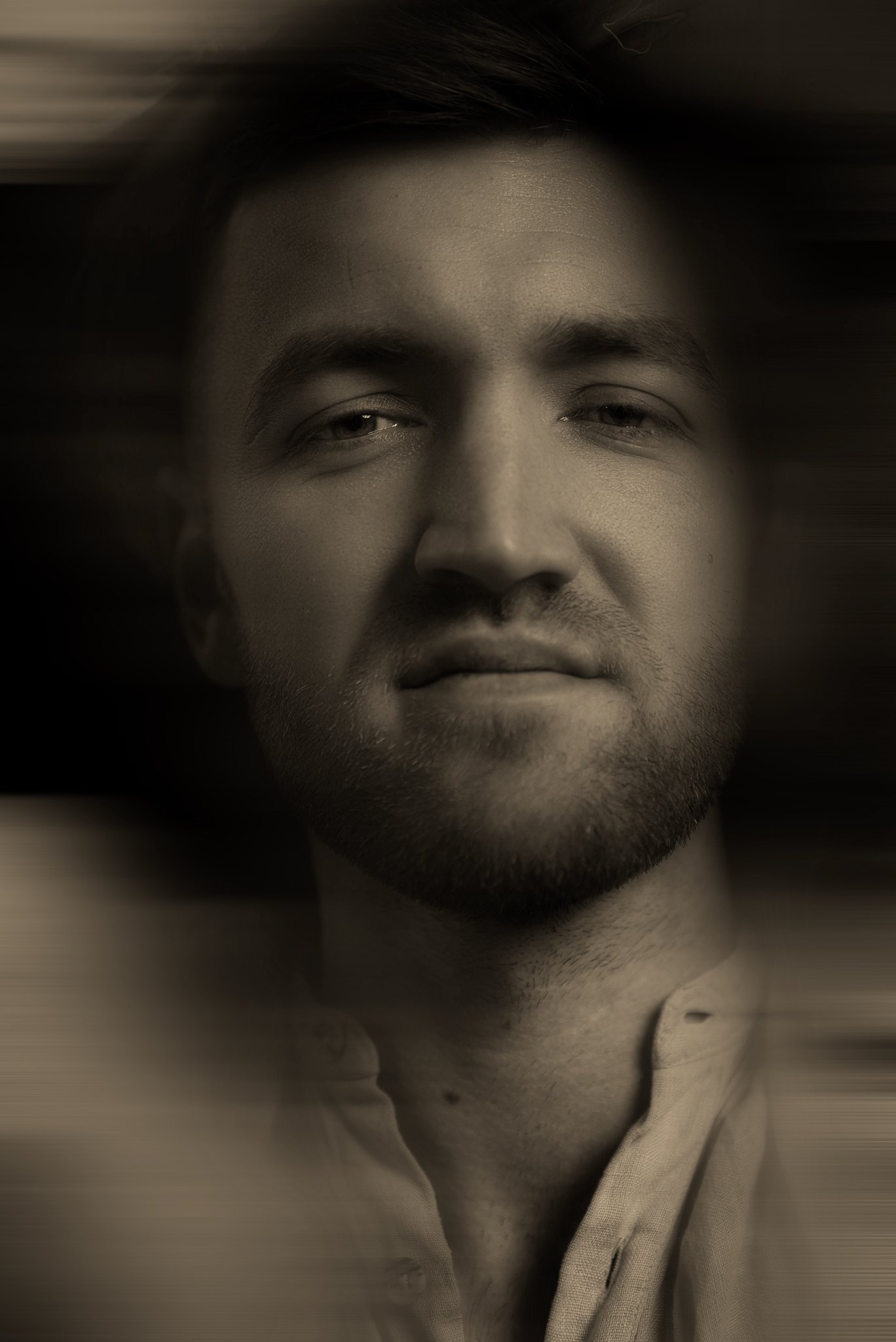 Schwarz-weiß-Porträt eines Mannes mit mittellangem Haar und Bart, entspannt und mit halbgeschlossenen Augen.