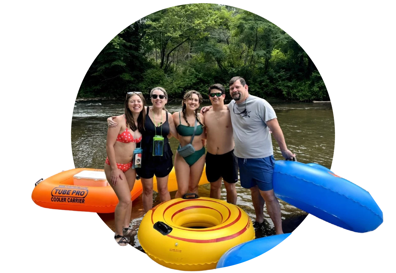 Group of five people standing in a river with trees in the background, holding inflatable tubes and enjoying a summer day.