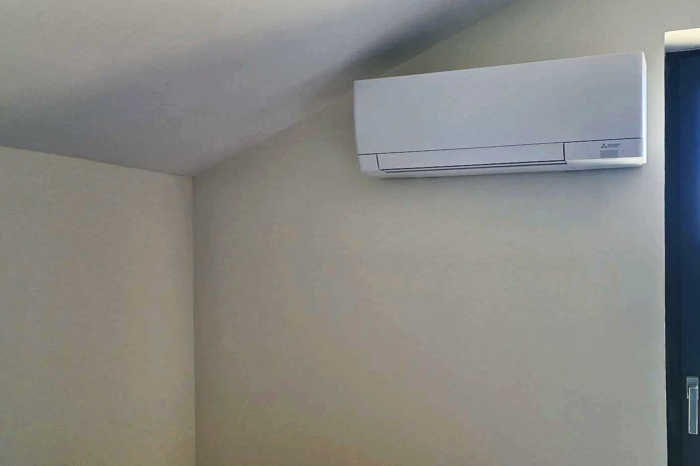 Climatisation murale blanche dans une pièce avec mur beige.