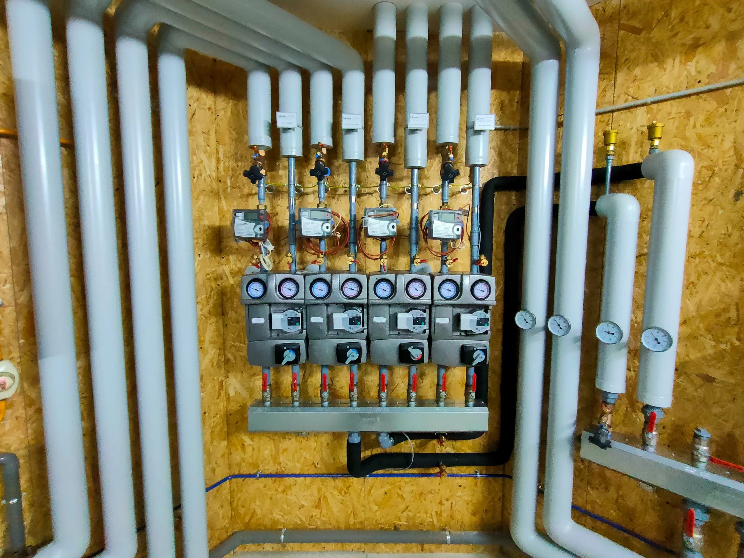 Un panneau de montage avec de nombreux tuyaux, manomètres, et vannes, utilisé pour la régulation de fluides dans un bâtiment ou une usine.