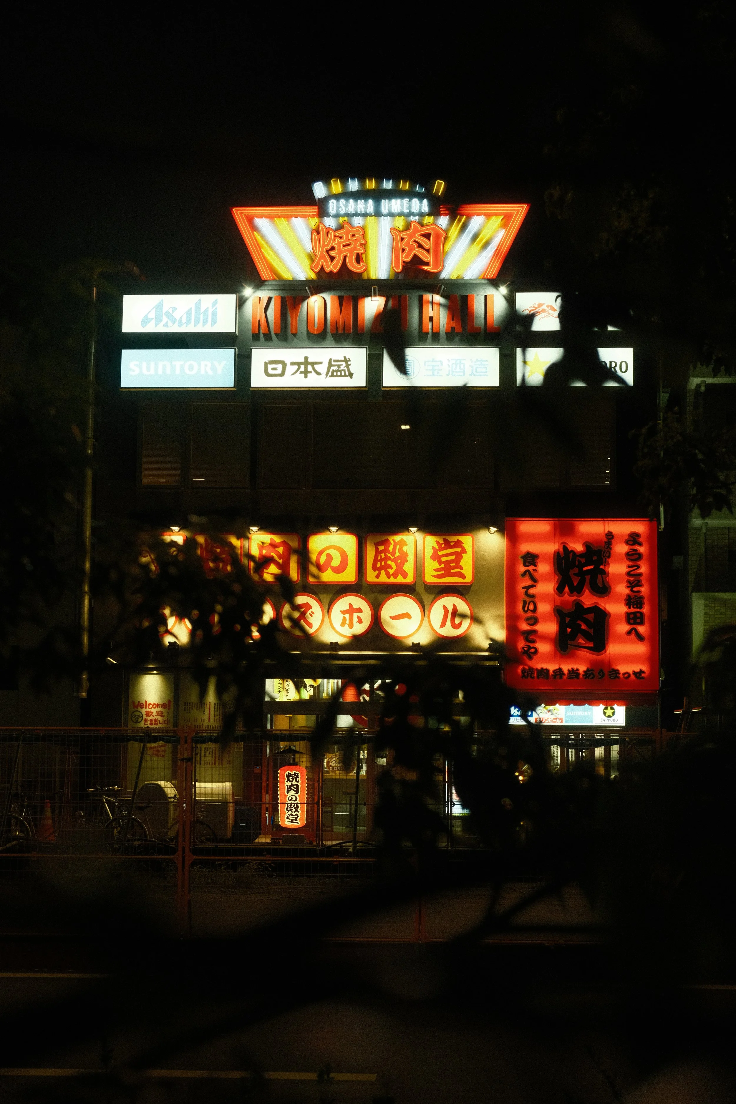 Straßenszene mit leuchtenden Neon-Schildern in einer japanischen Stadt nachts.