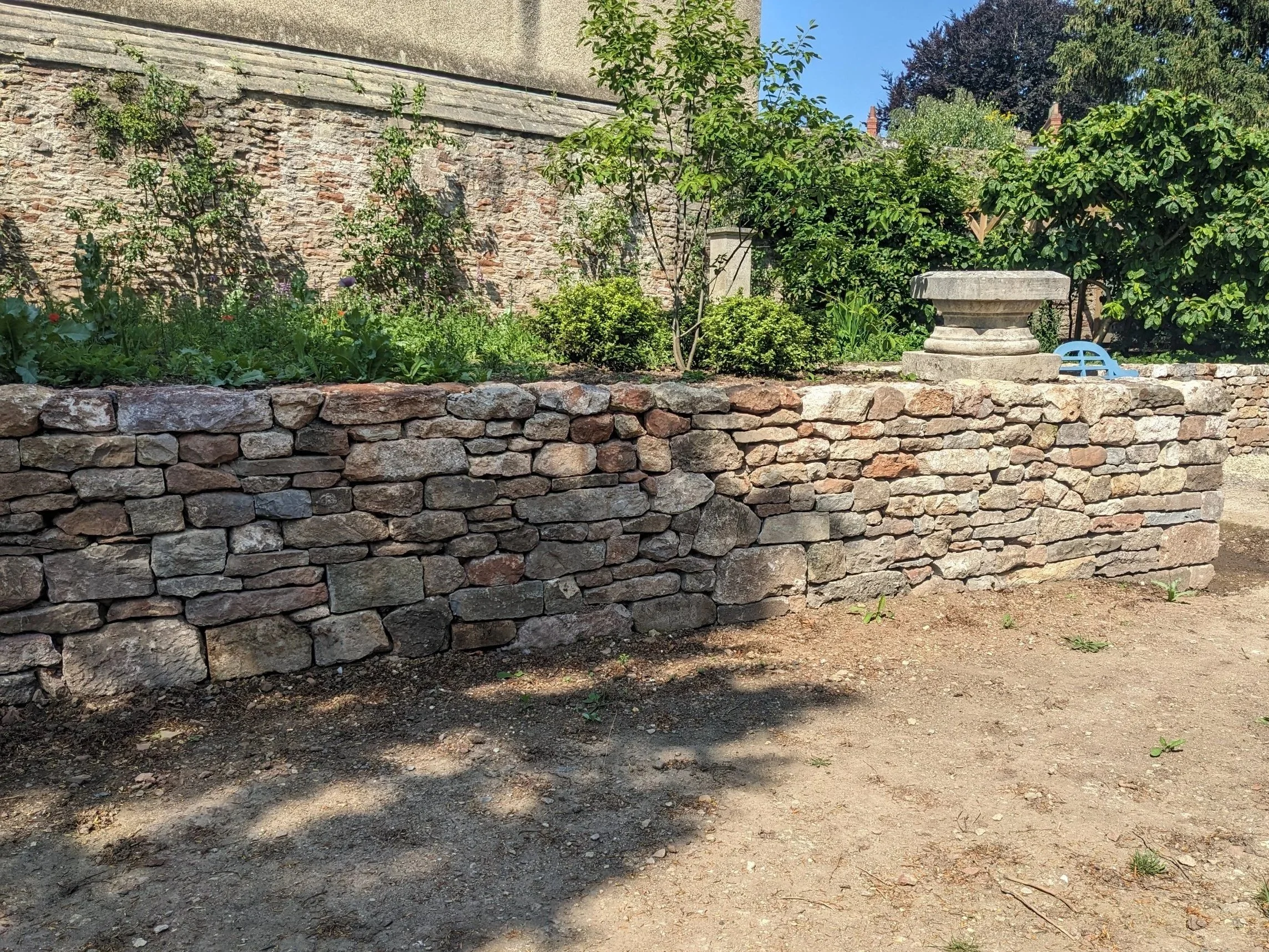 A stone wall in the heart of Wells in a landscaped garden of a grade 1 listed building.