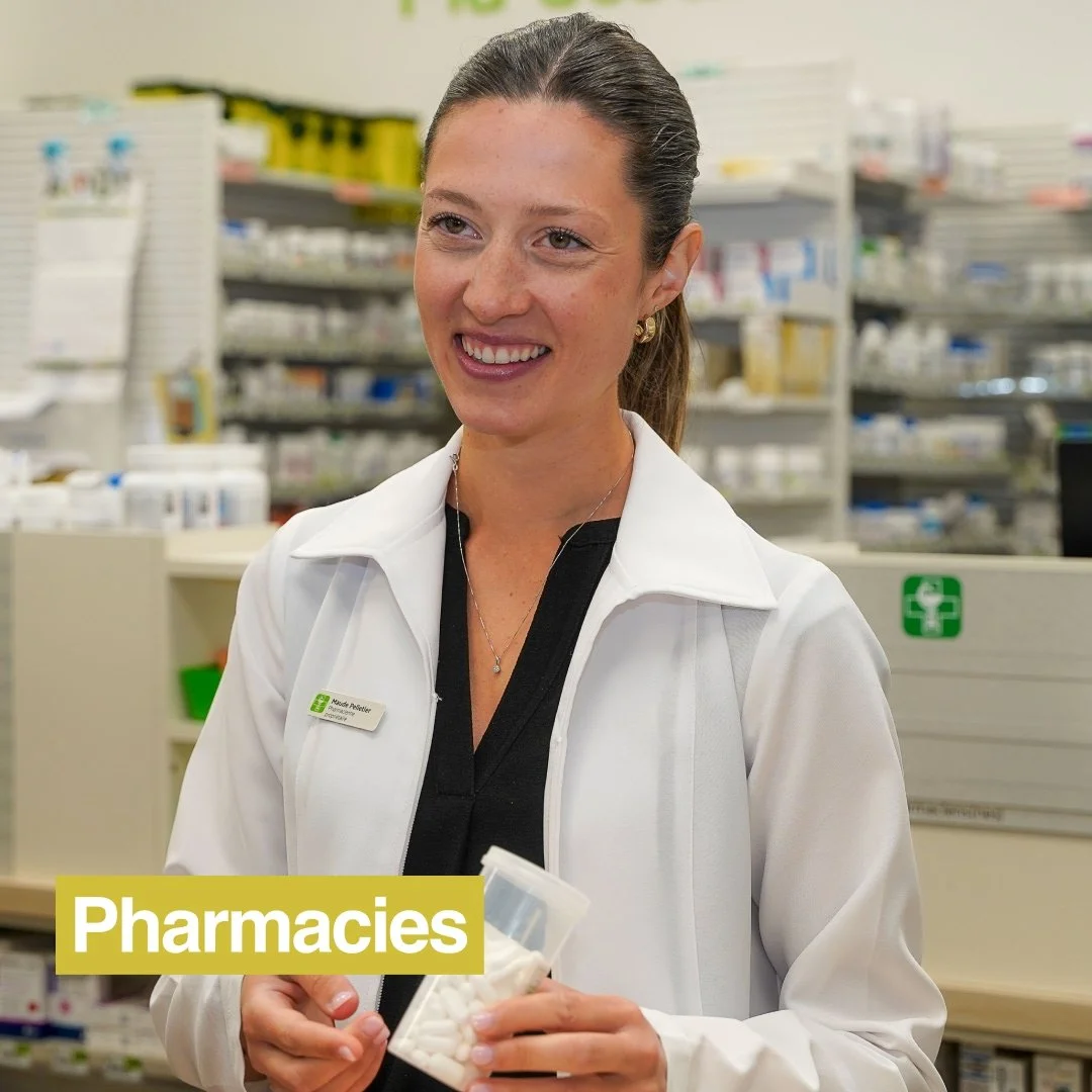 Pharmacienne avec son sarrau blanc souriant en remettant des médicaments au client face à elle