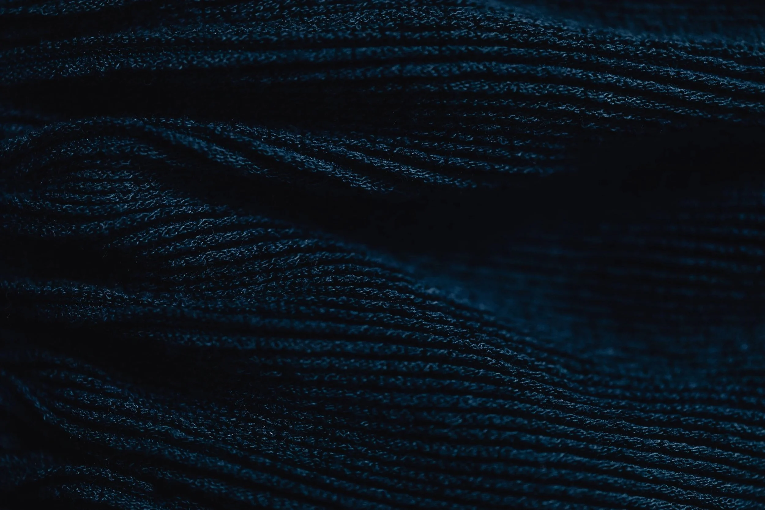 Zoom sur une surface de tissu en fibres tissées, de couleur sombre avec des reflets bleus.