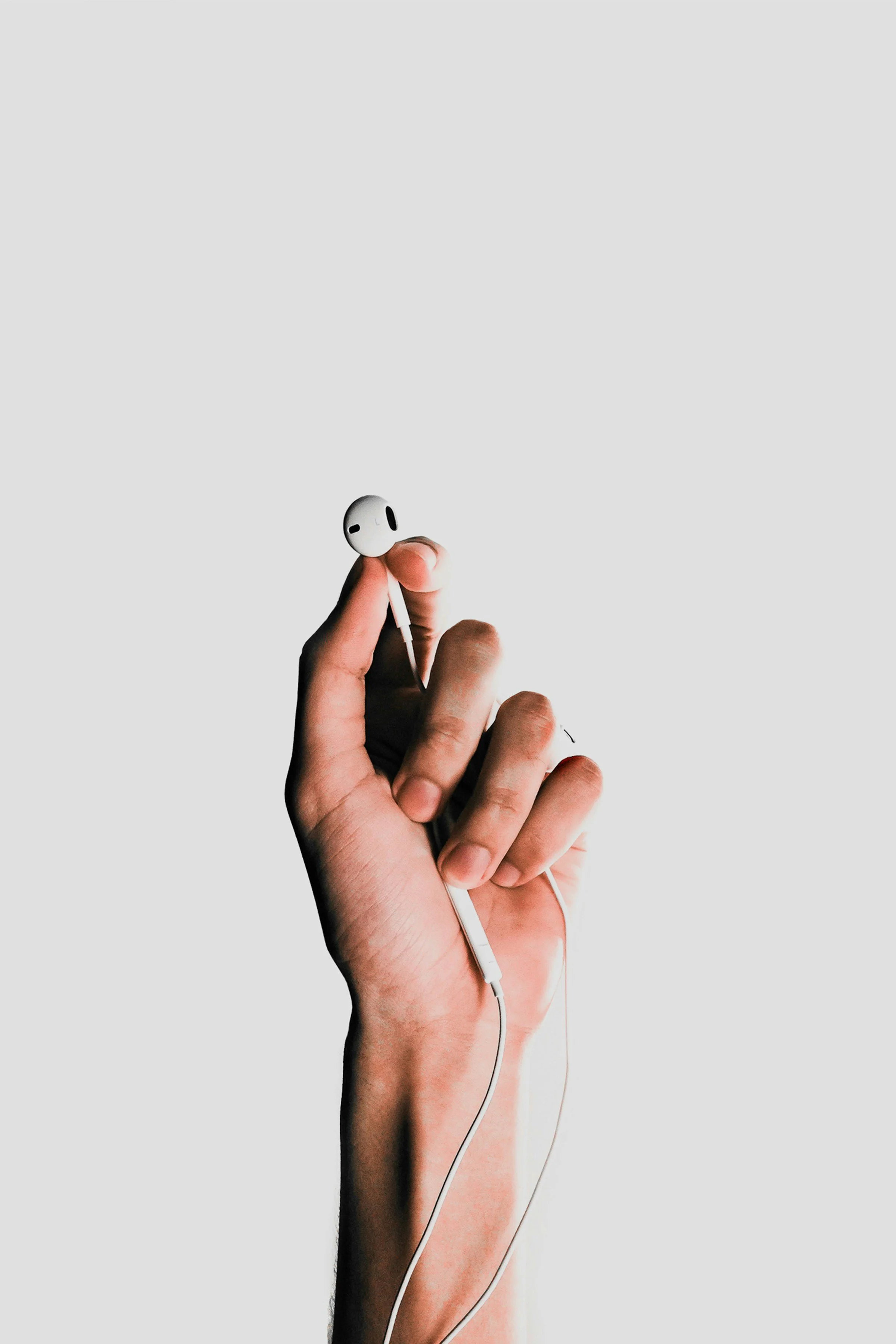 Hand holding a white wireless earbud
