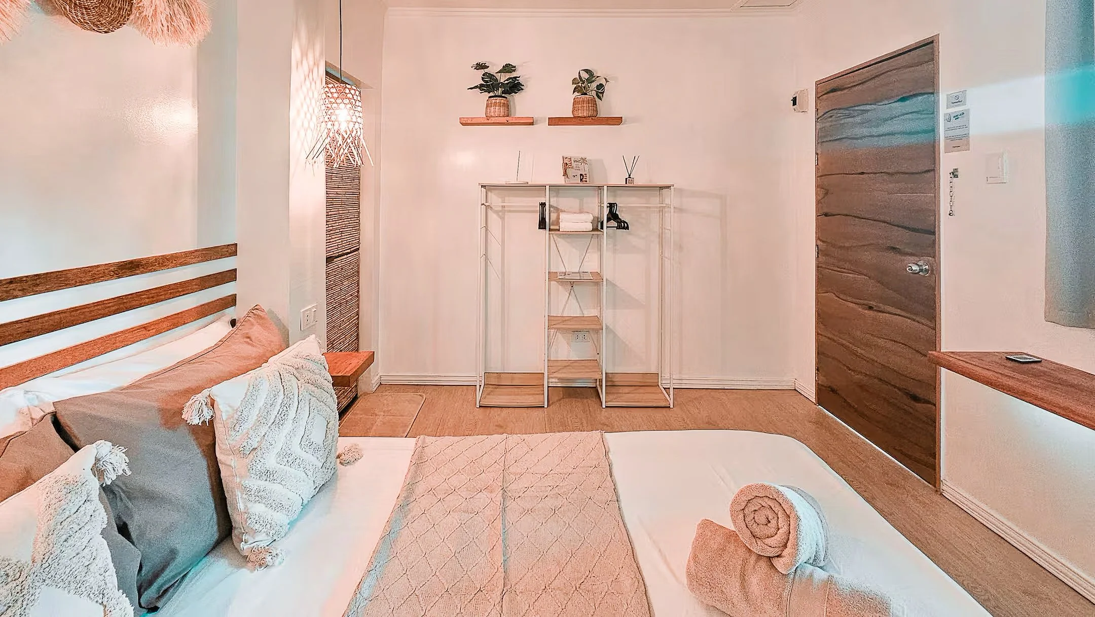 Bedroom view of Surf and Chill Room 3 in Siargao showing bed, open storage rack, and soft lighting.