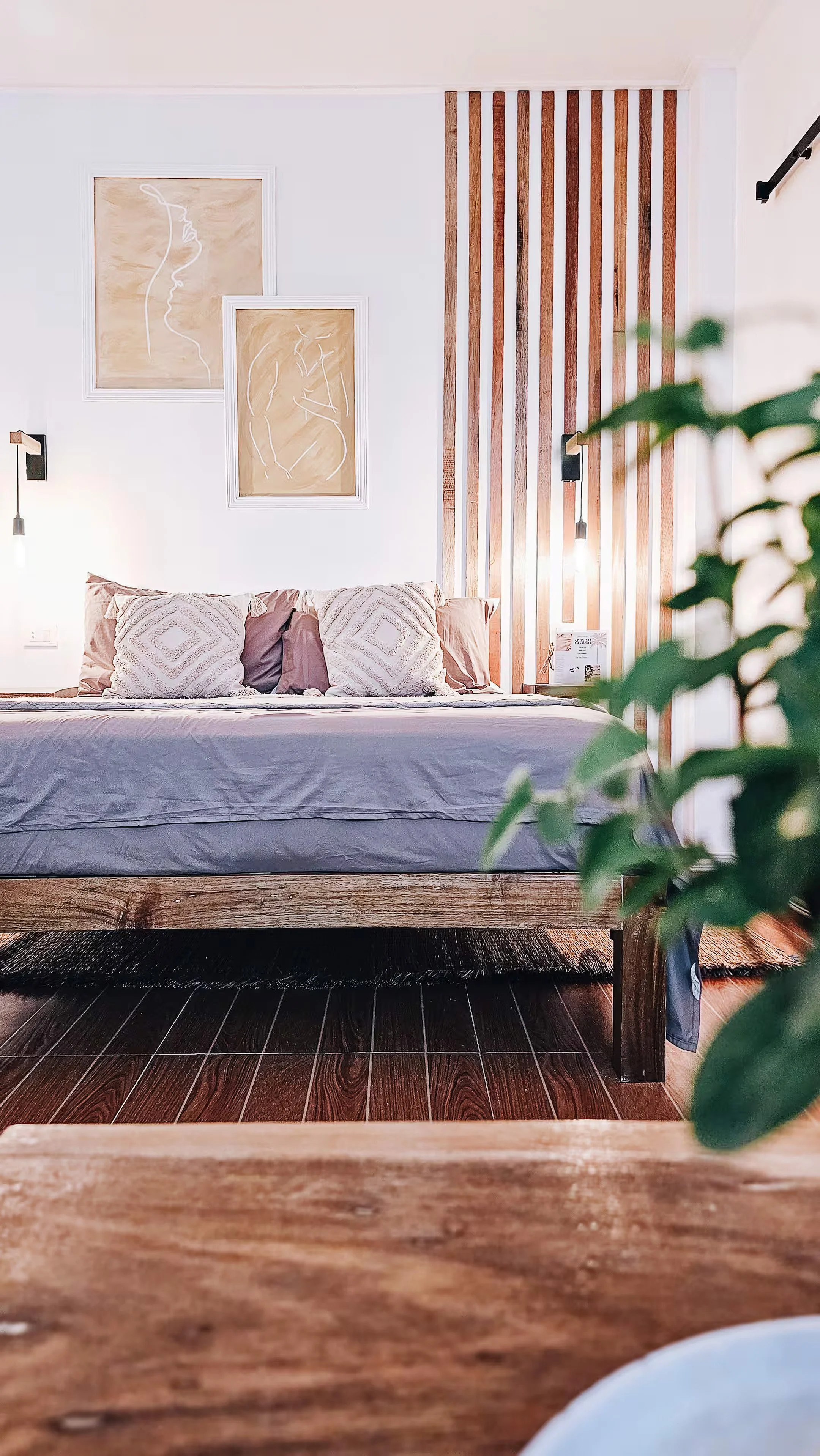 Queen bed in Room 1 at Surf & Chill Siargao with textured pillows, wooden wall accents, and soft lighting.