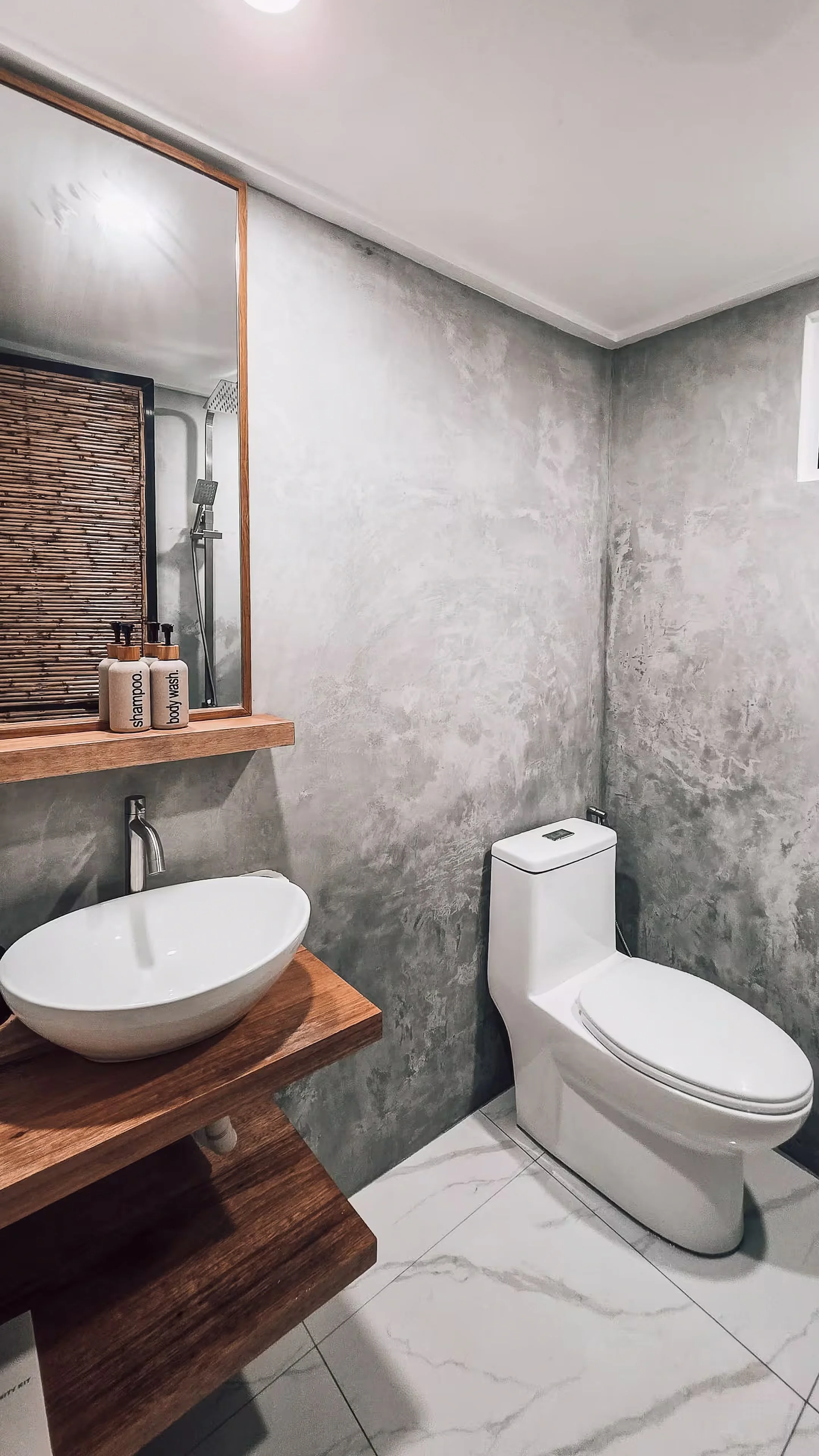 The bathroom of Surf & Chill Room 3 in Siargao features a clean, minimalist design with polished concrete walls, wooden accents, and a vessel sink that reflect the room’s natural island aesthetic.