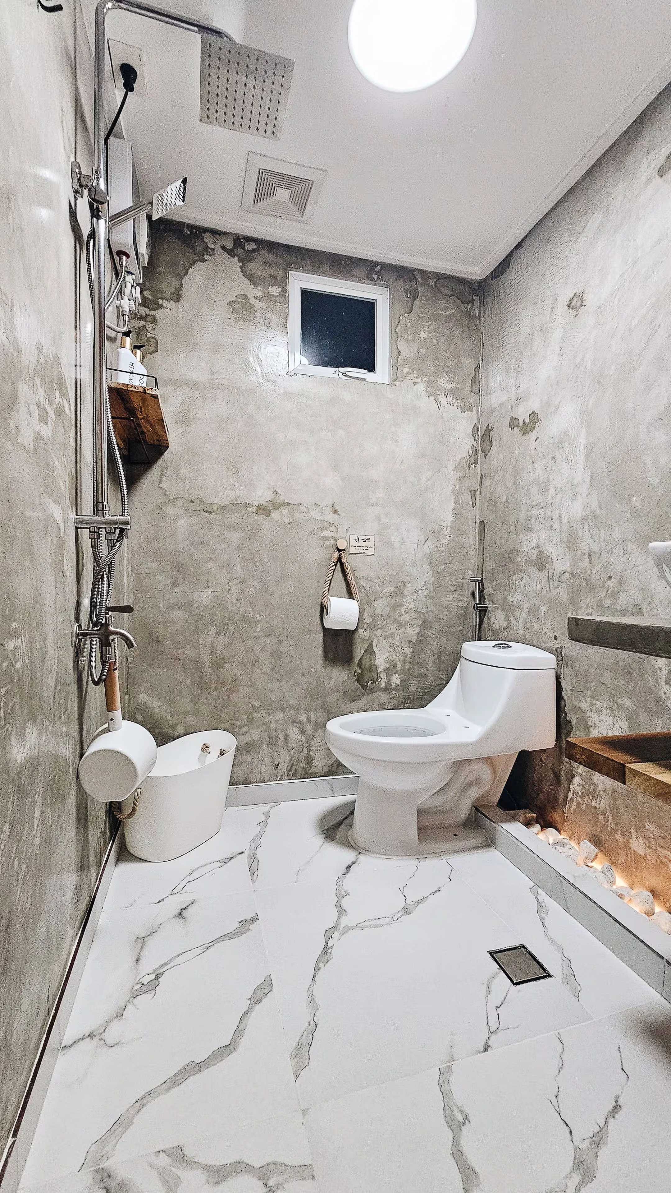 Private bathroom in Room 2 at Surf & Chill Siargao with concrete walls, rainfall shower, and modern fixtures.