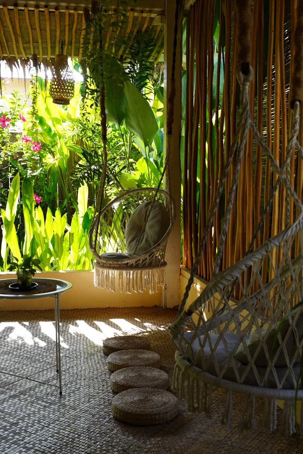 Surf and Chill Siargao chill space with hanging chairs and garden view, open-air tropical common area with plants and natural light
