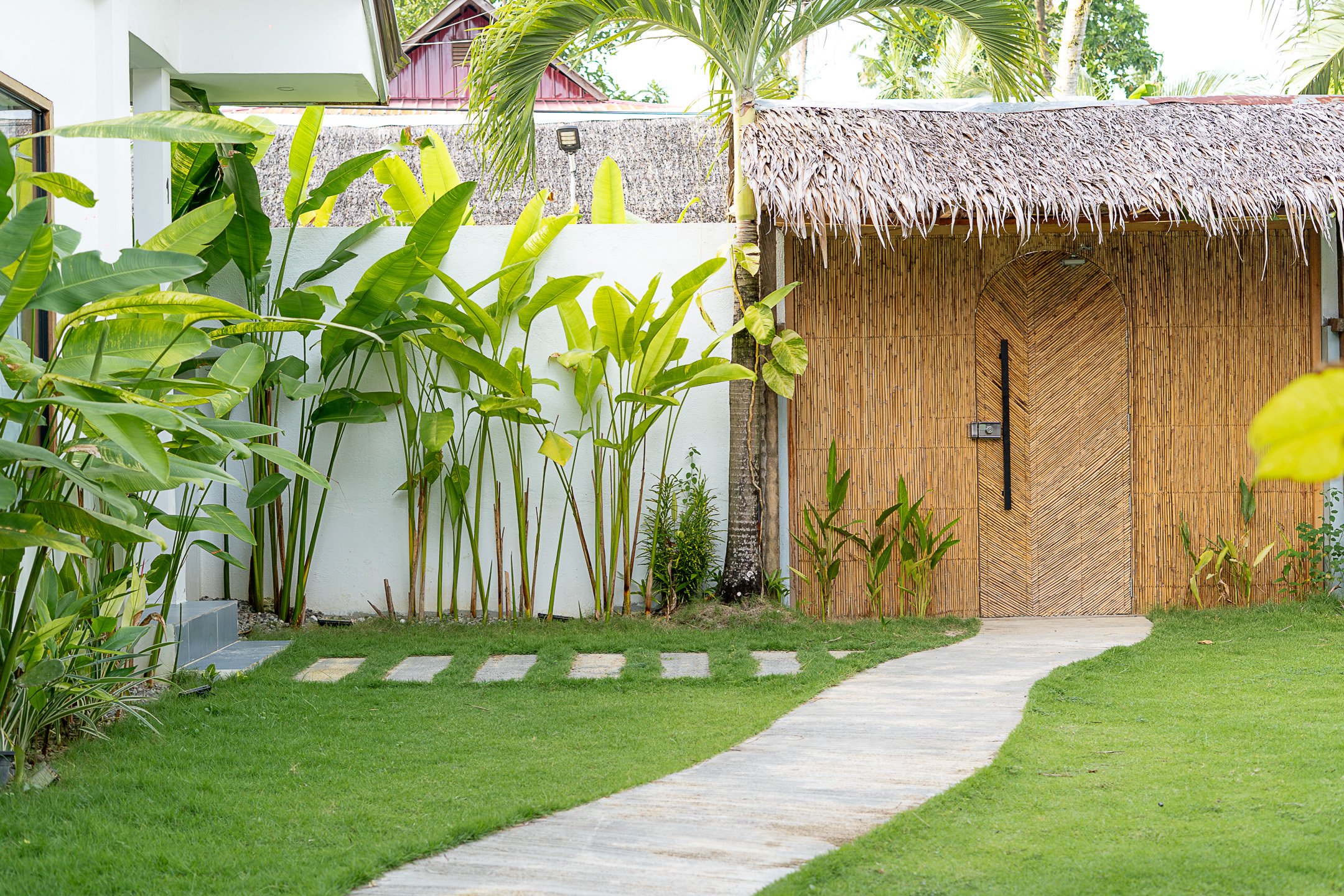 White Palm Villas Siargao garden pathway leading to a bamboo gate within a tropical private villa compound with lush greenery