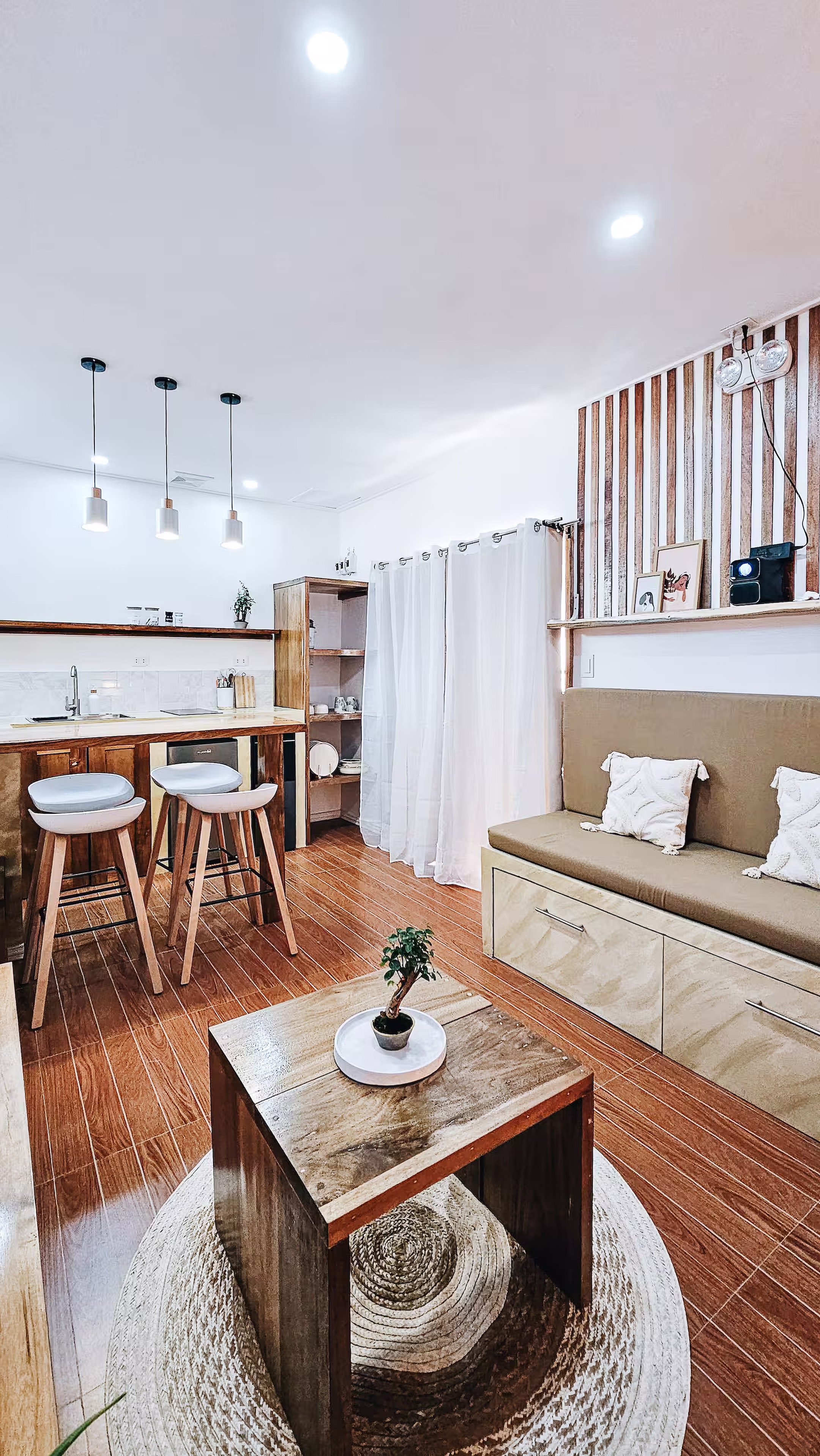 Bright living space in Room 1 at Surf & Chill Siargao with kitchenette, wooden floors, and convertible sofa.