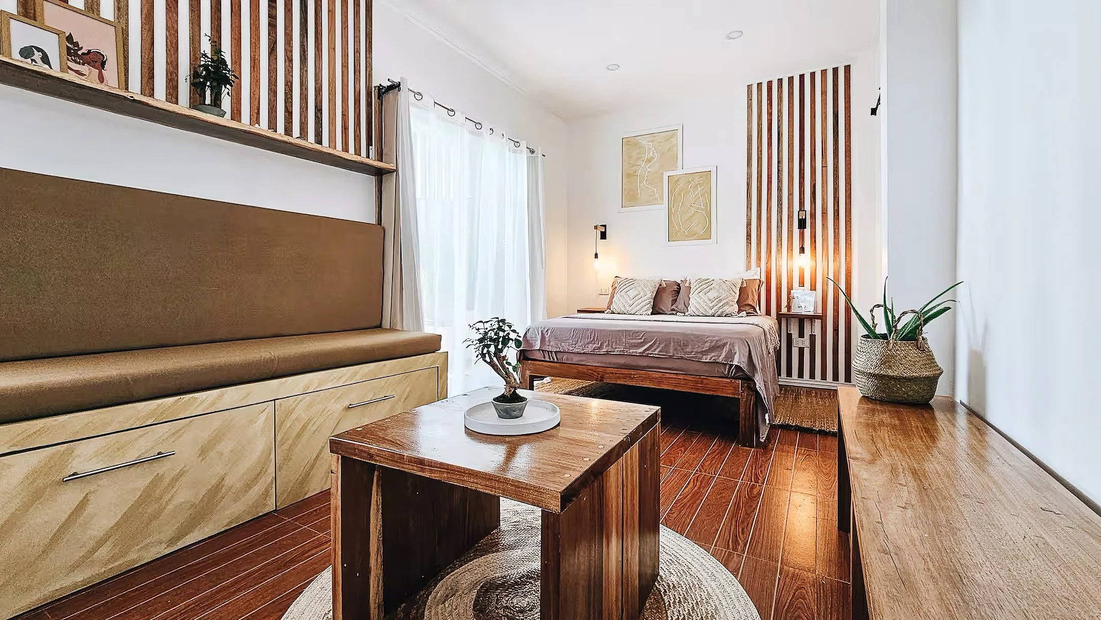 Room 1 at Surf & Chill Siargao featuring a cozy living area with sofa, coffee table, and queen bed in a bright wooden interior.