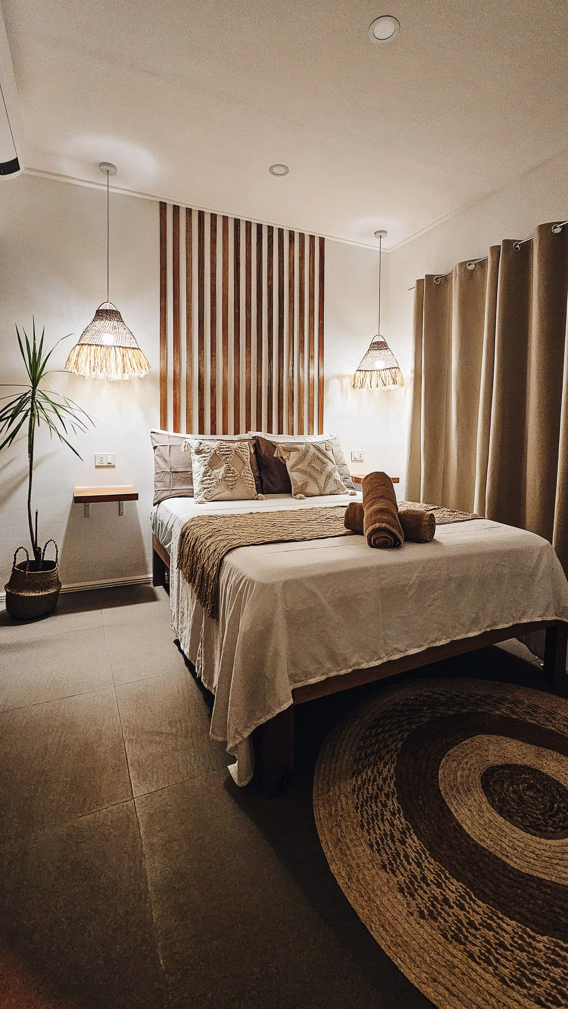 Room 2 at Surf & Chill Siargao featuring a double bed with rattan pendant lamps, warm lighting, and natural tones.