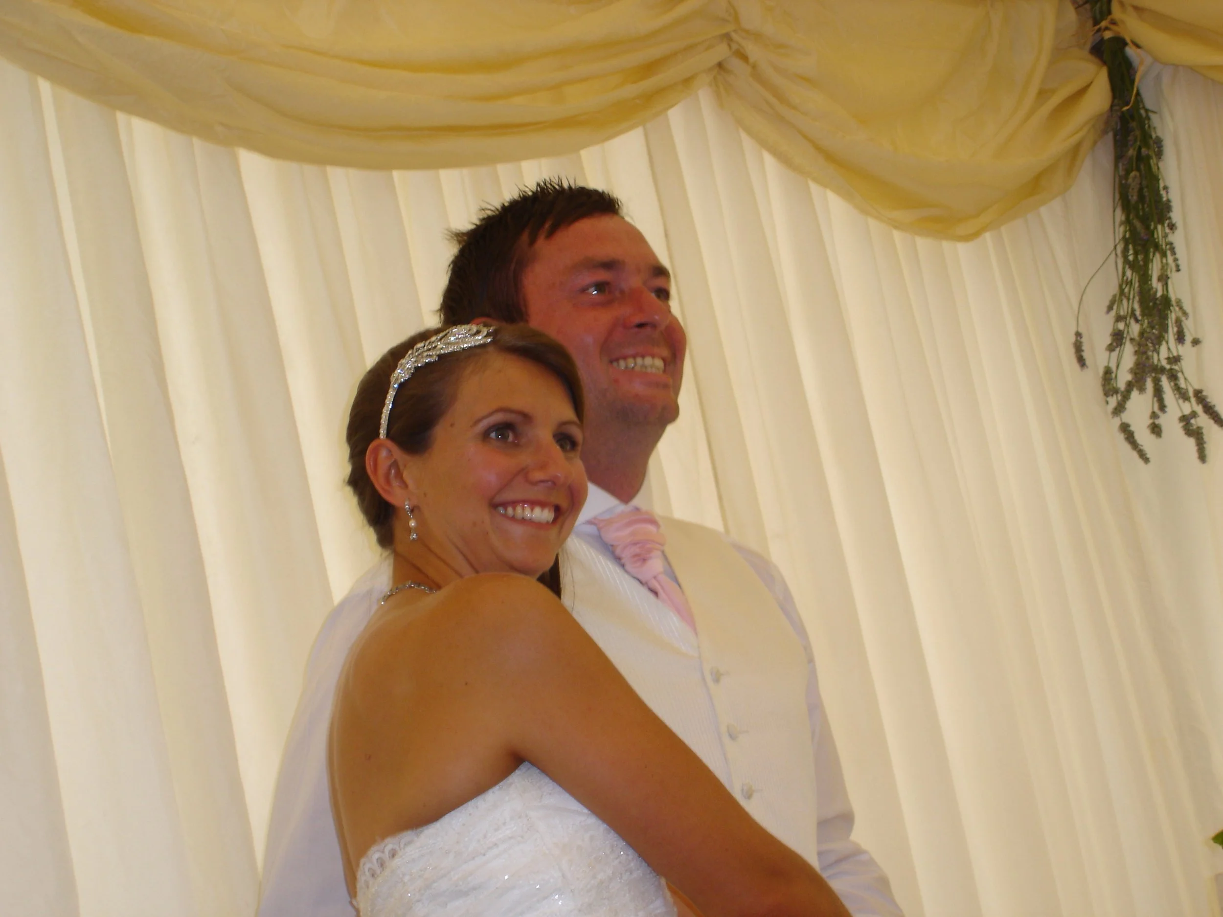 Man and woman posing in their wedding marquee