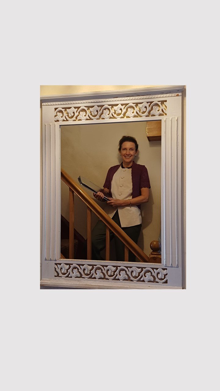 Rachel Peatfield celebrant, on stairs reflected in mirror with silver celebrant folder