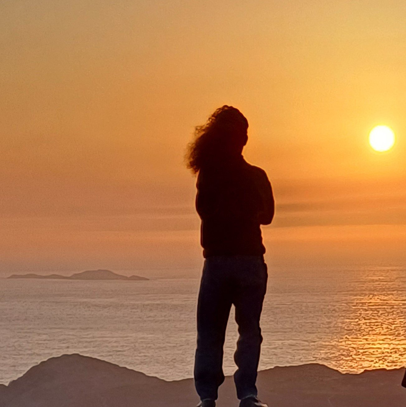 Long-haired teenager watching sunset over the sea