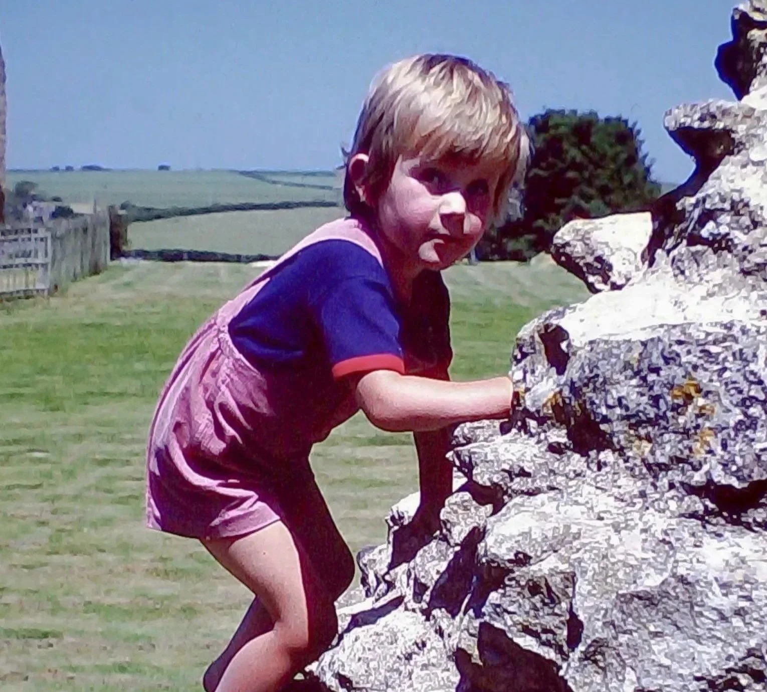 Child in shorts and t-shirt climbing a ruined wall