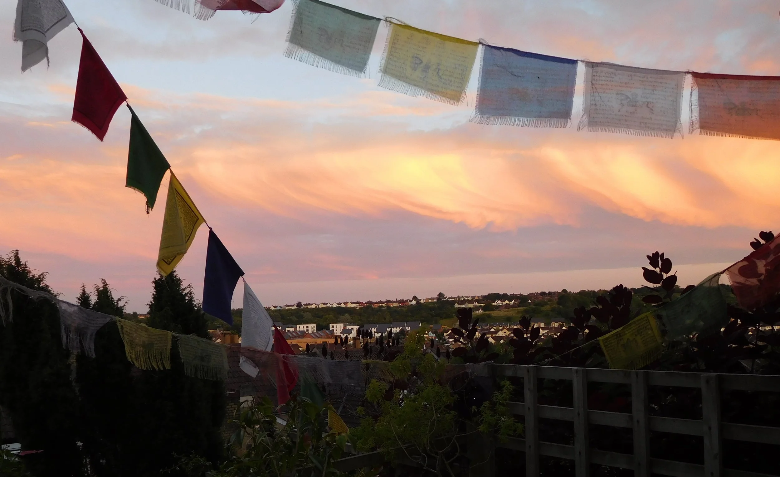 Prayer flags fluttering in the breeze with a view of a city hill