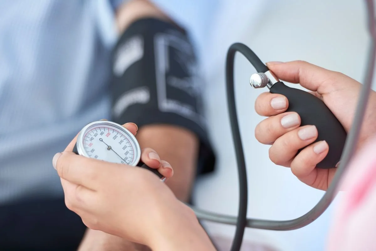 Neurovascular sugrgeon in london taking a patient’s blood pressure using a cuff and manual blood pressure monitor.